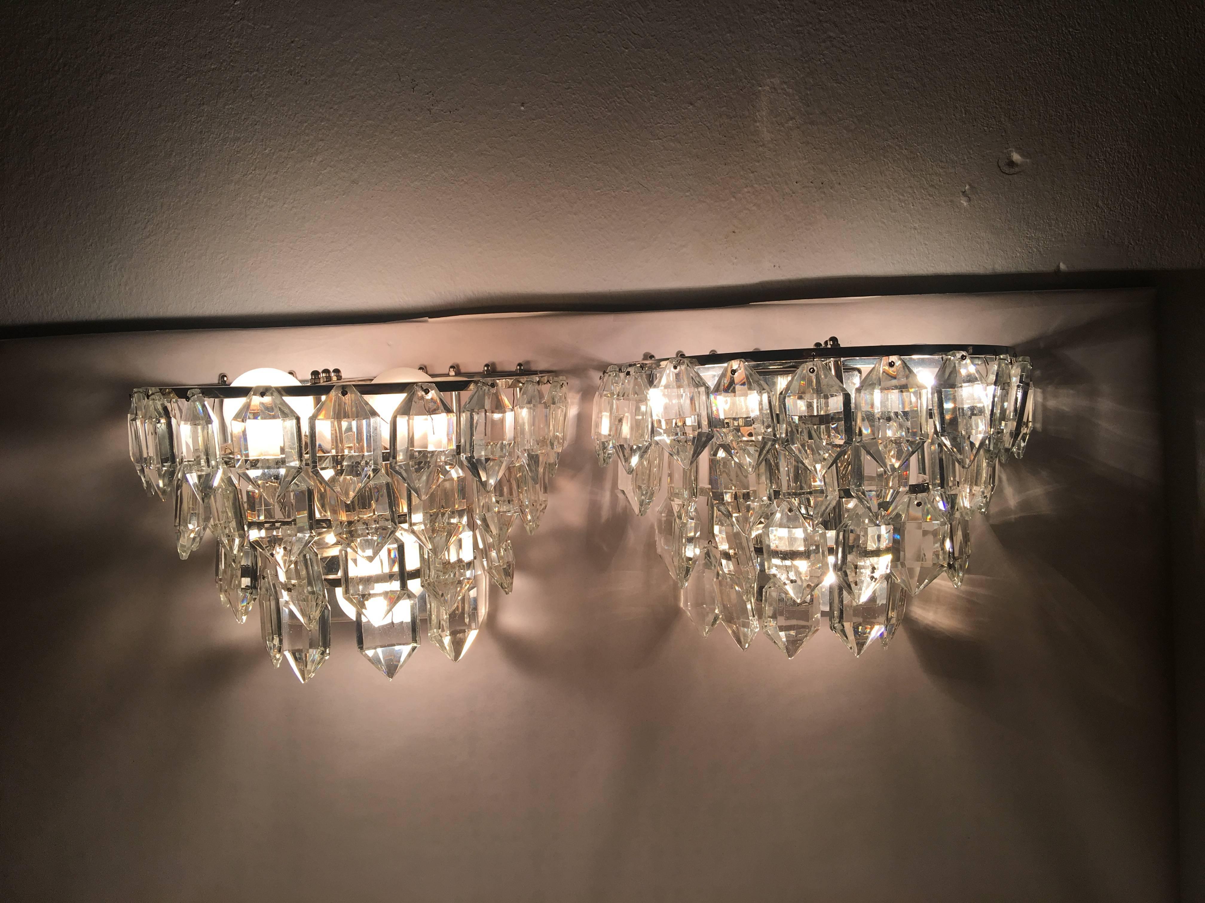 A elegant pair of Austrian sconces with four tiered crystal on a silver plated fixture. Each fixture requires three European E 14 candelabra bulbs, each bulb up to 40 watts. Price listed is for pair.
