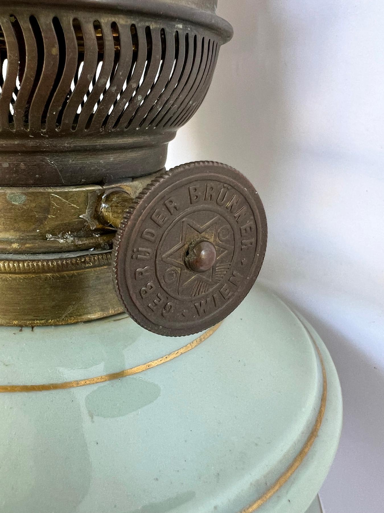 each urn decorated with white, lavender and gray arabesque and Moorish motifs all on a celadon ground; adorned with finely chased gilt-bronze mounts; fitted with its original oil lamp fittings and marked 'Gebrüder Brünner, Wien'; height: 14
