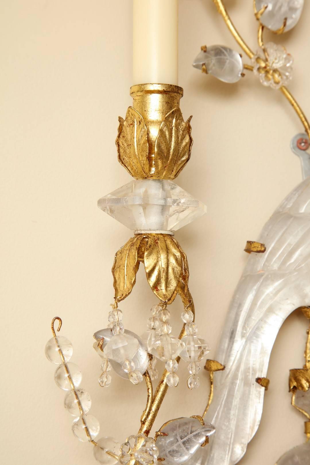 Paire de nouvelles appliques à deux lumières en métal doré et cristal de roche, tournées vers la droite et la gauche, représentant des oiseaux perchés sculptés dans du cristal de roche et entourés de gerbes de branches et de feuilles, avec