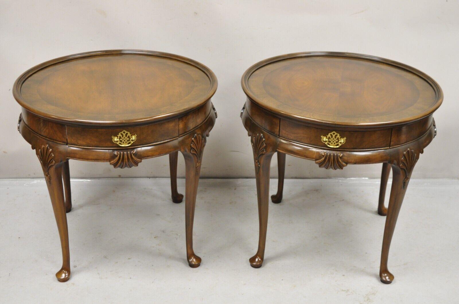 Pair Baker Furniture English Queen Anne Style Burl Walnut Round Side End Tables. Item features a single dovetailed drawer, banded inlay tops, original labels, finished backs, nicely carved details, quality American craftsmanship. Circa Mid to Late