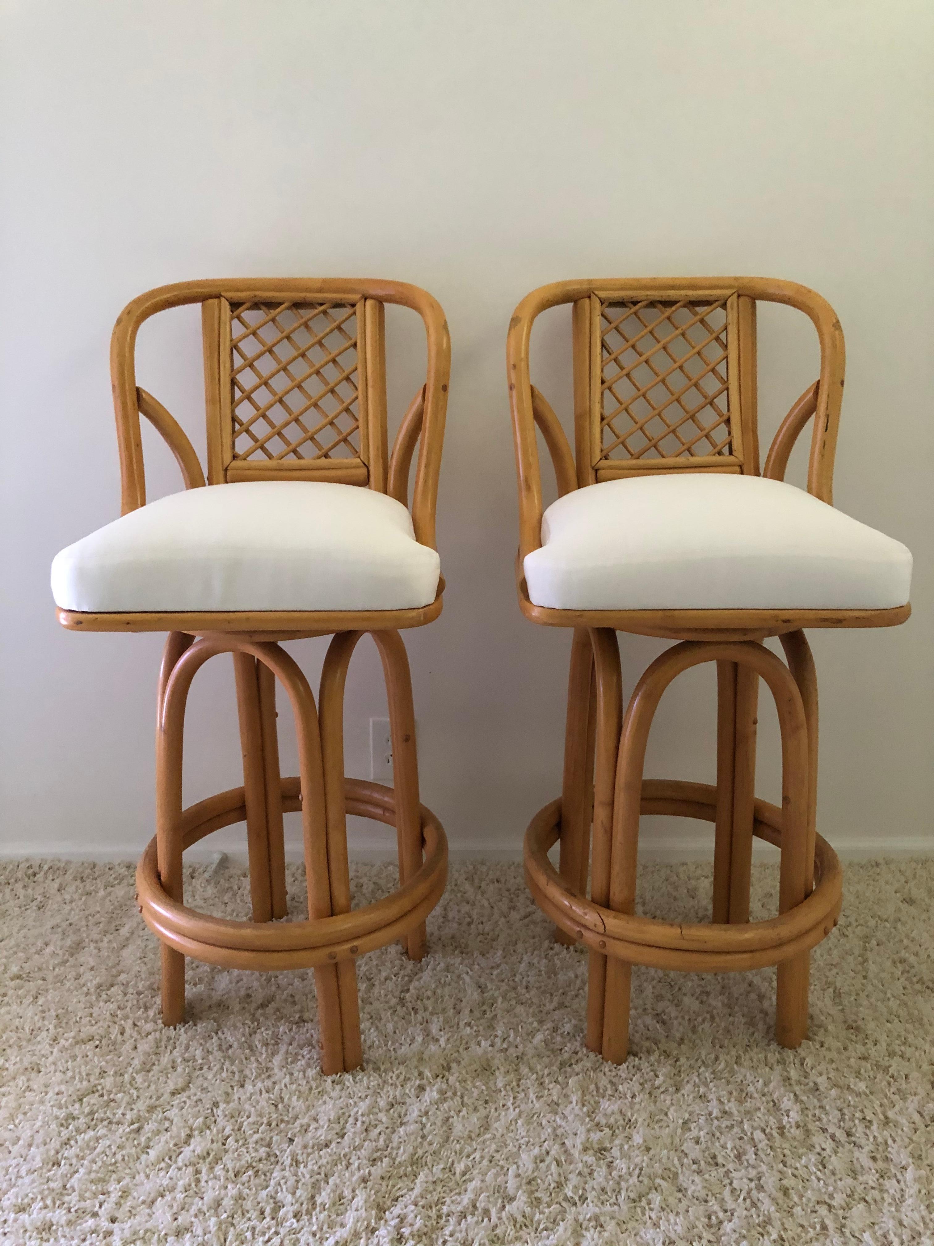 Pair of bamboo tall swivel bar stools, off-white woven sunbrella fabric.