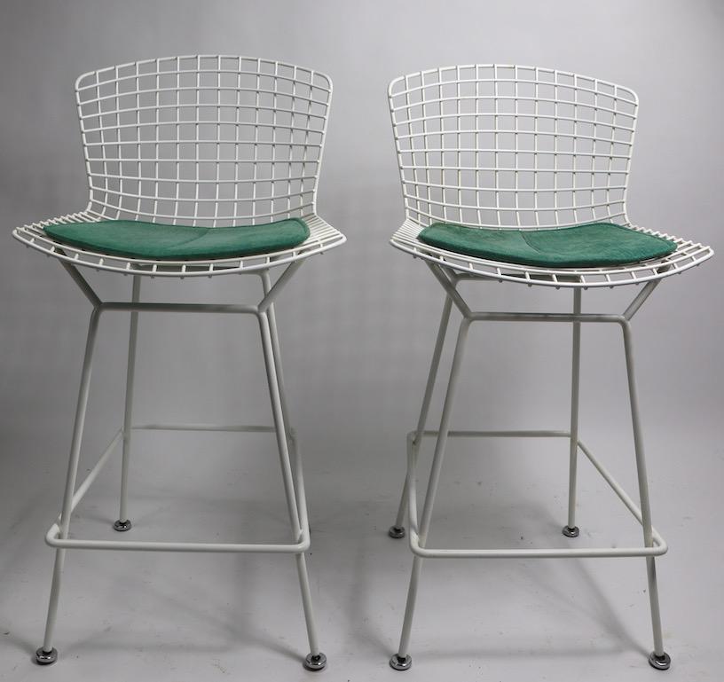 Classic and iconic Bertoia for Knoll bar or counter height stools in white with green fabric pads. Architectural design, clean original condition, ready to use. Both pads retain original Knoll label. Offered and priced individually, however we would