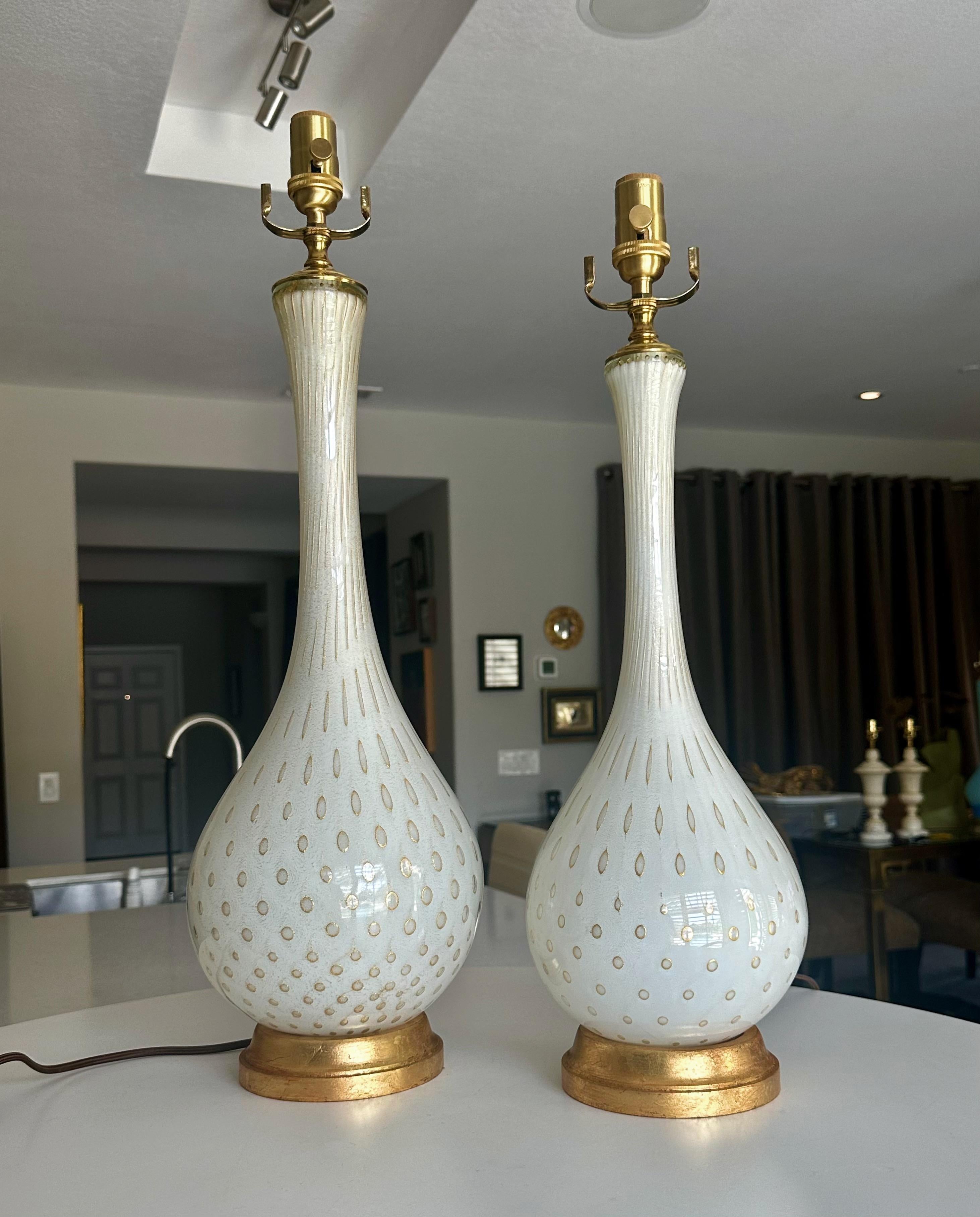 Pair of similar Murano Italian handblown white and gold controlled bubbles glass table lamps by Alfredo Barbini. The lamps rest on giltwood bases, rewired with new brass 3 way sockets and rayon covered cords. The lamps are exact except for