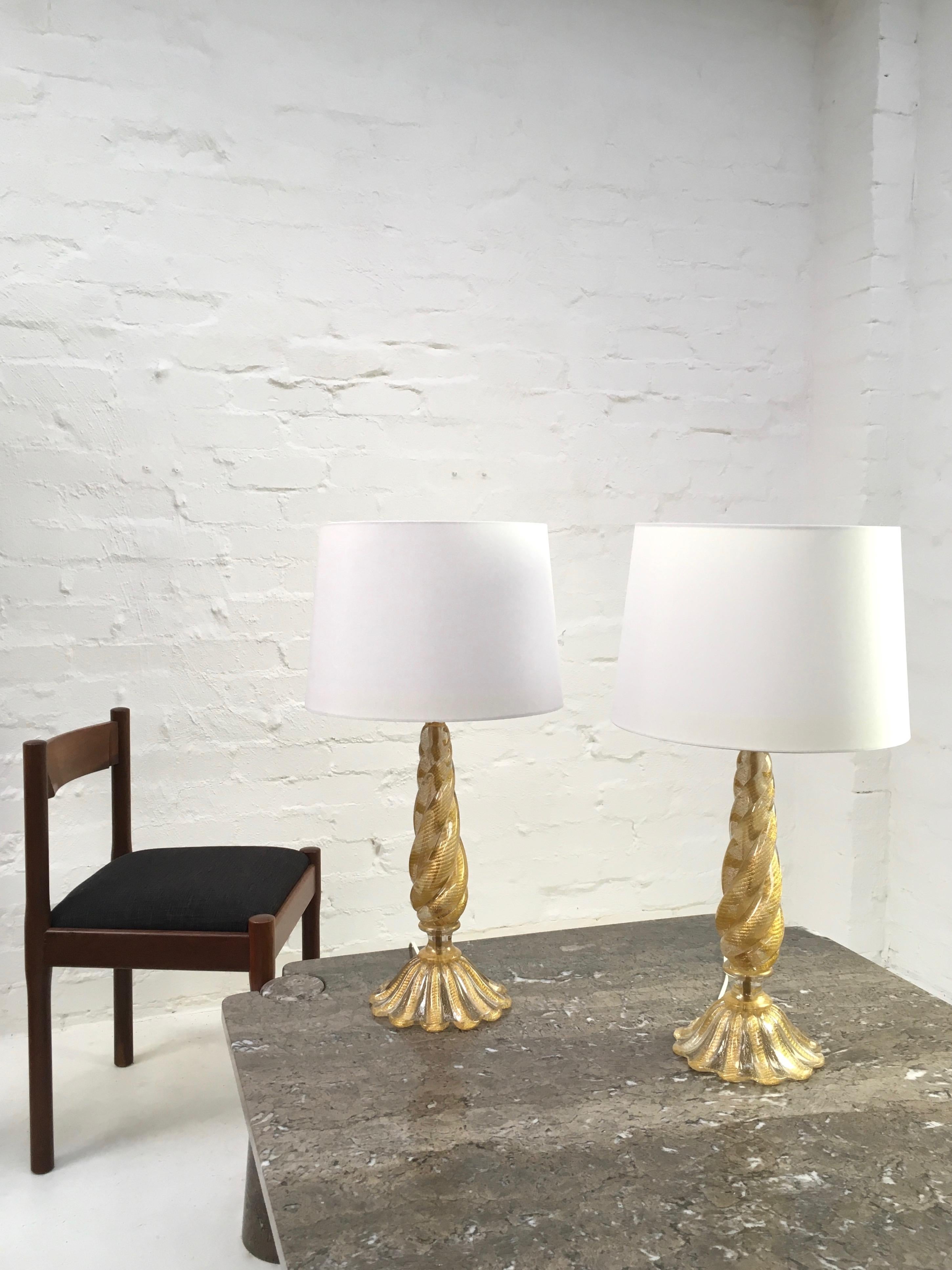 A pair of table lamps by Barovier and Toso, dating to the 1950s, with gold leaf inclusions in the ‘Cordonato d’Oro’ technique. They appear as twisted ropes of gold in each section of glass. 

These rare examples include an impressive stem of