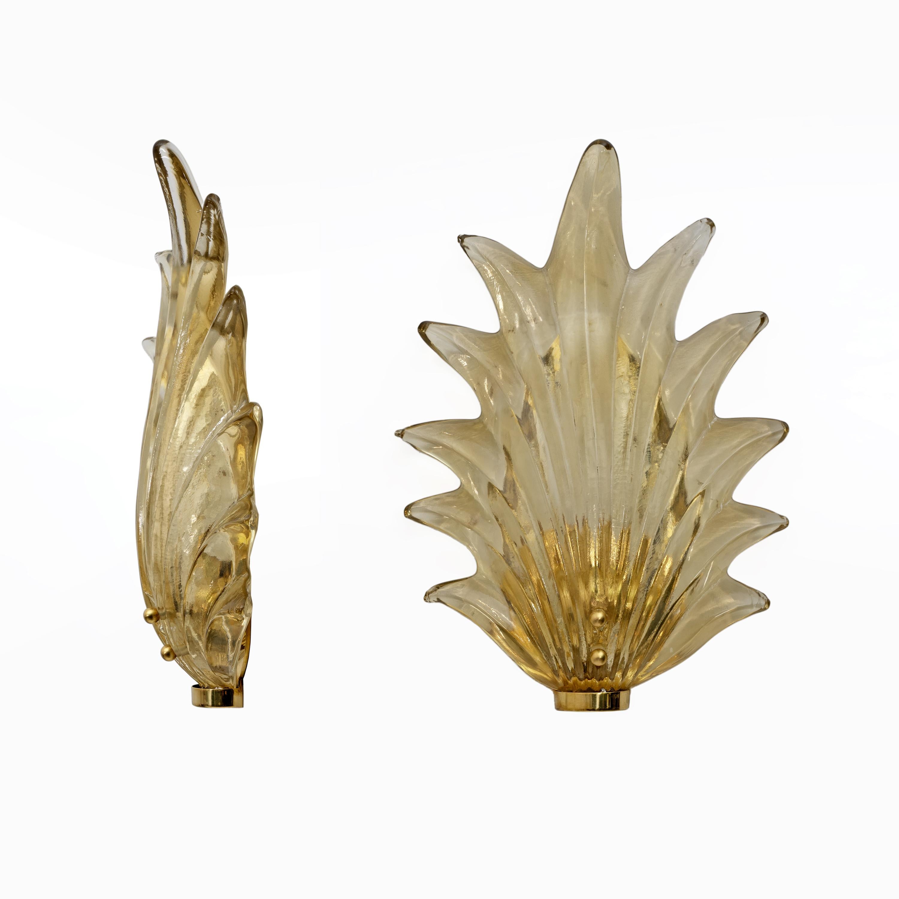 Stunning Murano glass leaves in a beautiful amber yellow hue, accented by a polished brass base. The sconces consist of a brass frame secured to the wall with dowels and a large amber yellow Murano glass leaf inserted into its housing. The leaf has