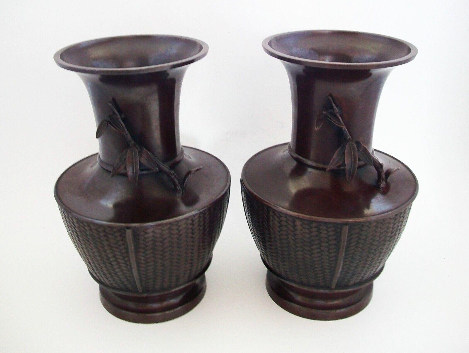 Vintage pair of fine Asian bronze vases - featuring basket weave panels to the lower body and applied 'bamboo branches with leaves' to the necks of each vase - stepped base and flaring mouth - original reddish brown finish and dark patina - each