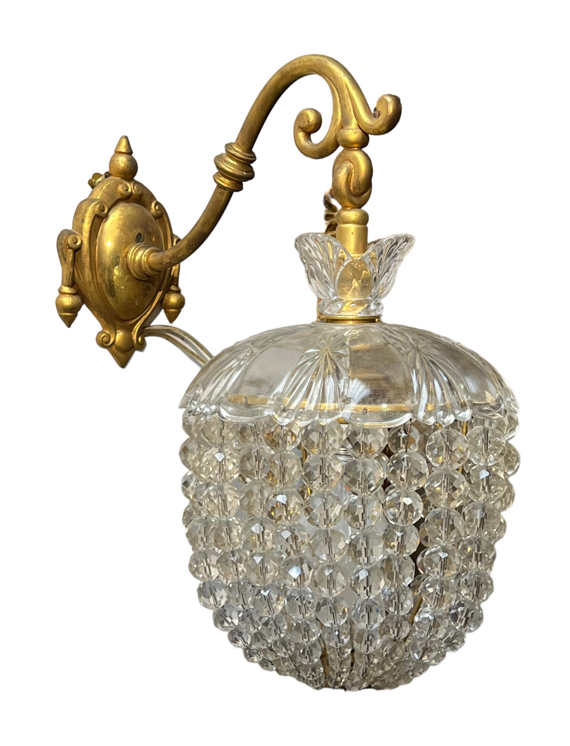 Our pair of gilt bronze sconces, circa 1900, have a single socket with canopy of spherical cut crystals and molded glass cover at top. Attributed to Baccarat.