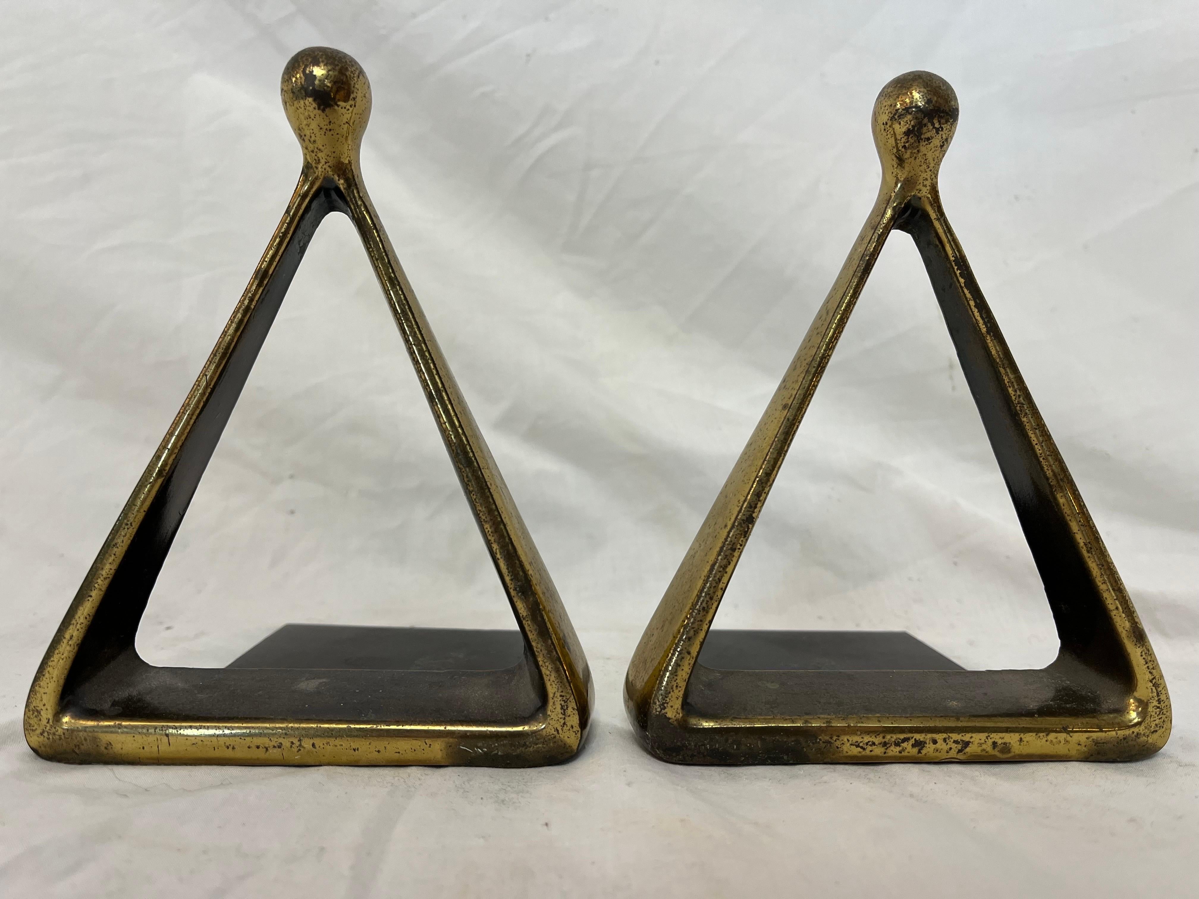 A chic and iconic pair of triangle or stirrup bookends by Ben Seibel. These Classic examples of Mid-Century Modern design are well loved with patination and oxidation to the surface. Embossed mark from Jenfredware, felt bottoms and paper labels all