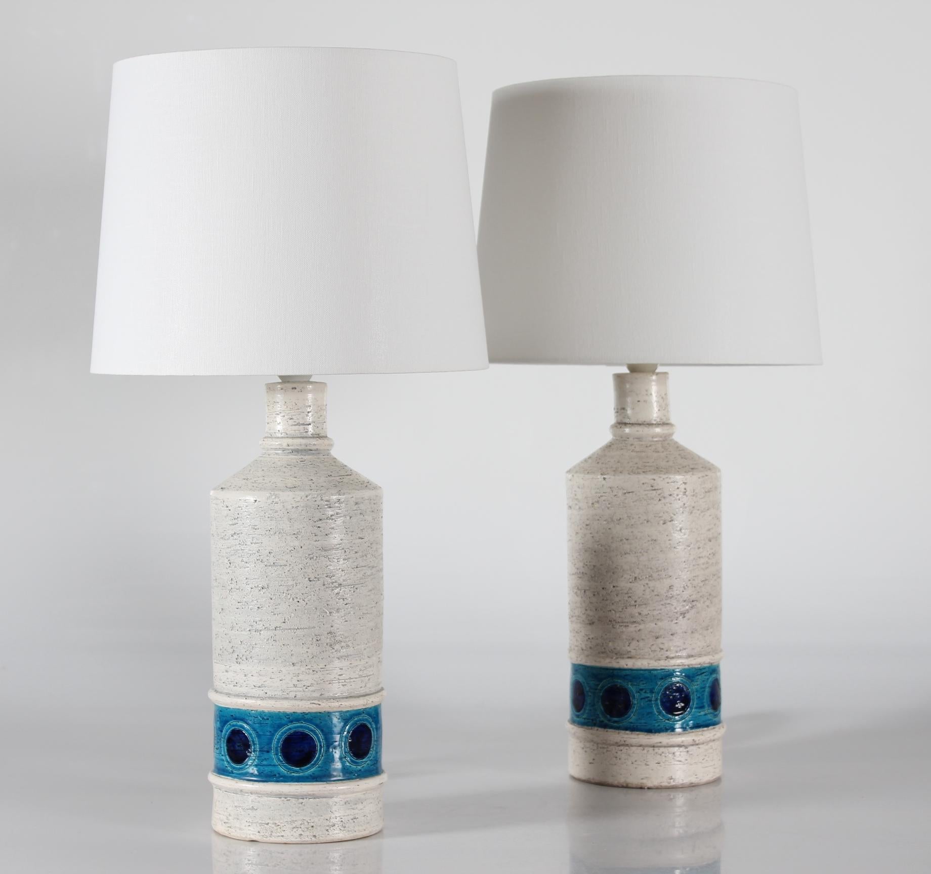 Pair of vintage Aldo Londi Bitossi table lamps with new quality lampshades

They have a rough white surface with a blue and black circle decor.

The lampshades are designed in Denmark and made of woven fabric with some texture and are natural