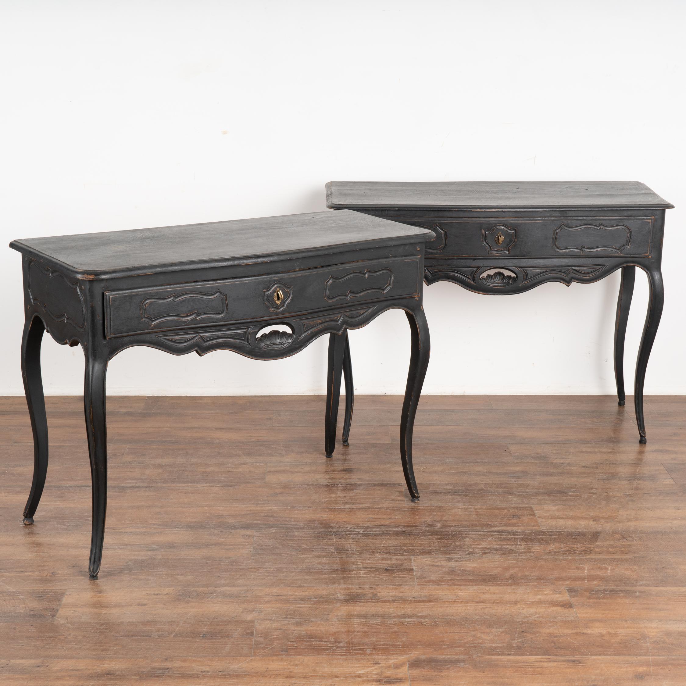 Pair of black painted oak side tables. The curved cabriolet legs, carved drawer, skirt and sides add a romantic appeal.
The newer, custom applied black painted finish has been lightly distressed to fit the age and grace of these delightful accent