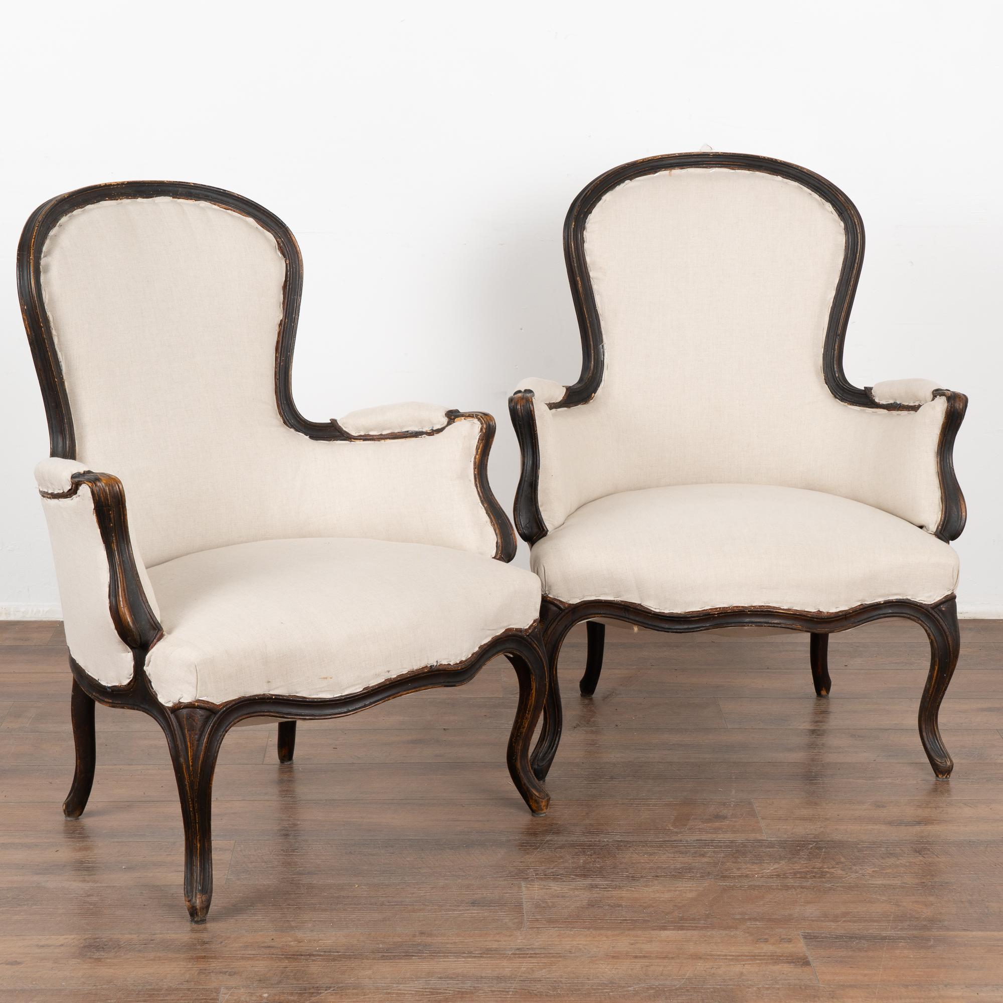 Pair, attractive Swedish country Gustavian arm chairs with gently curved back and arms, cabriolet legs.
Newer, professionally applied layered black painted finish has been lightly distressed and rubbed, adding to the grace of these lovely arm