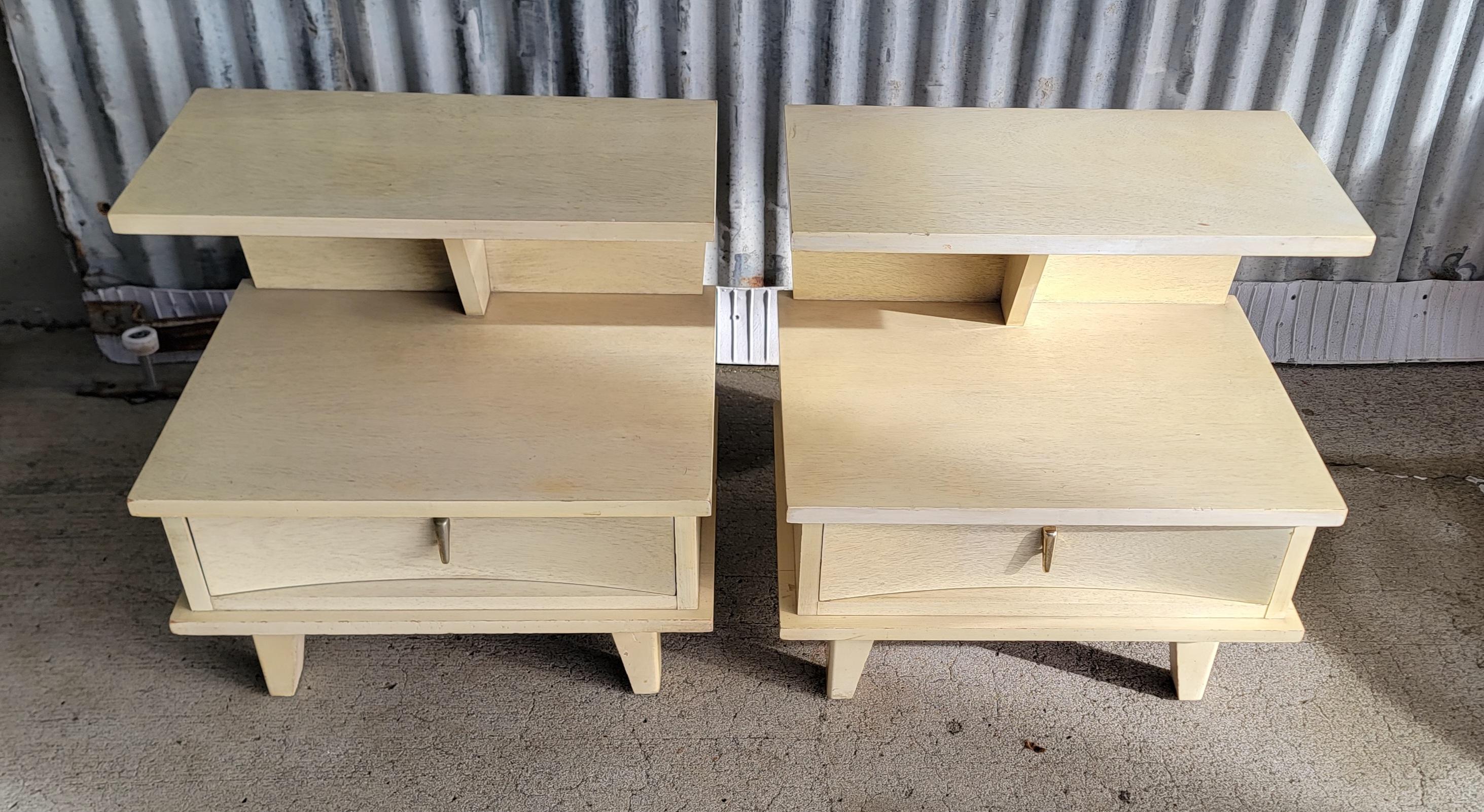A pair futuristic style Mid-Century Modern nightstands with various acute and obtuse angles. Two-Tier design, each with one drawer. All wood construction, dovetail to drawers with solid oak secondary woods. The original finish is a blonde / white