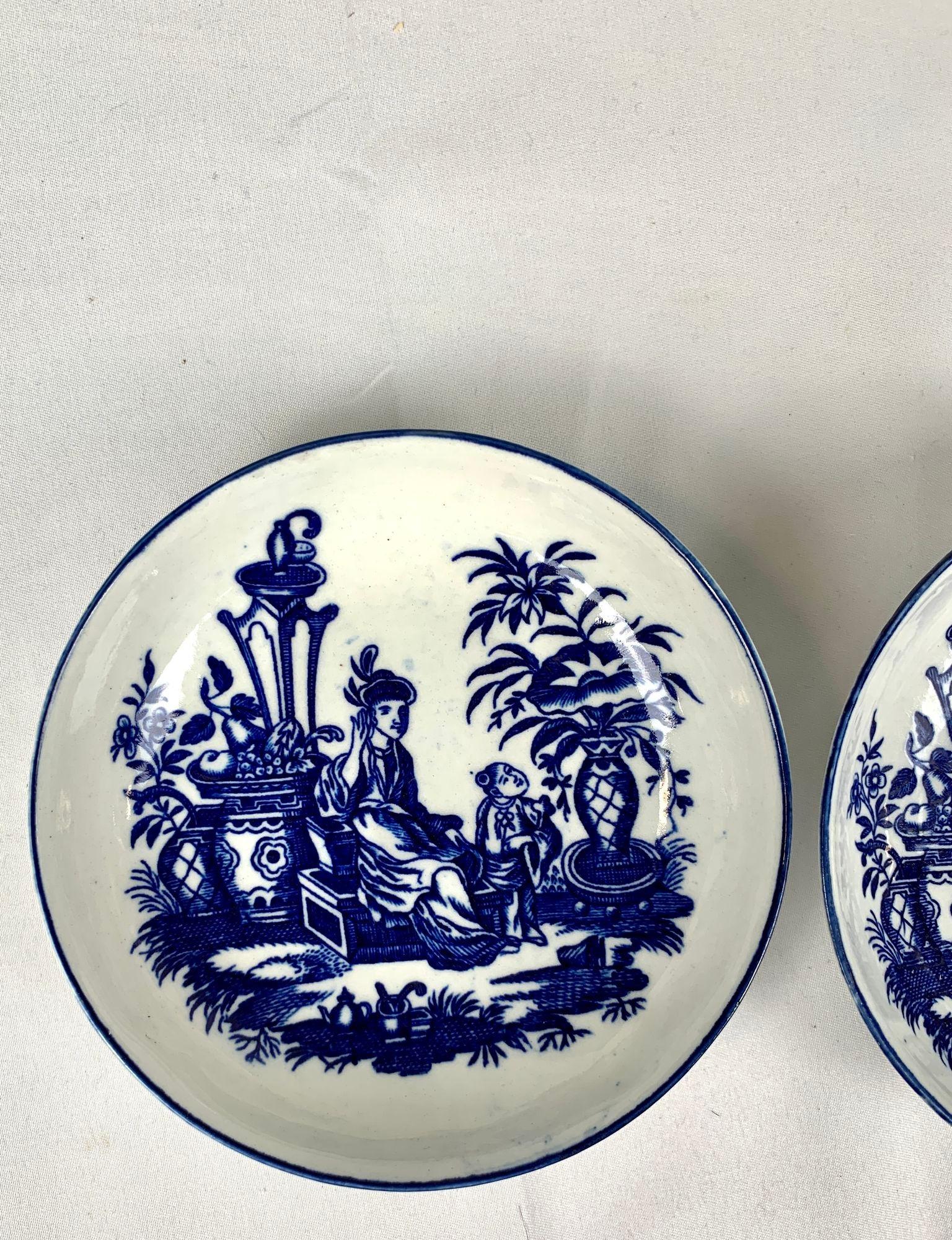 This pair of blue and white porcelain saucers was made by Caughley in England circa 1785.
Painted in underglaze blue, they show a lovely chinoiserie scene of a mother and son in a lush garden with flowering trees and several large vases.
The blue