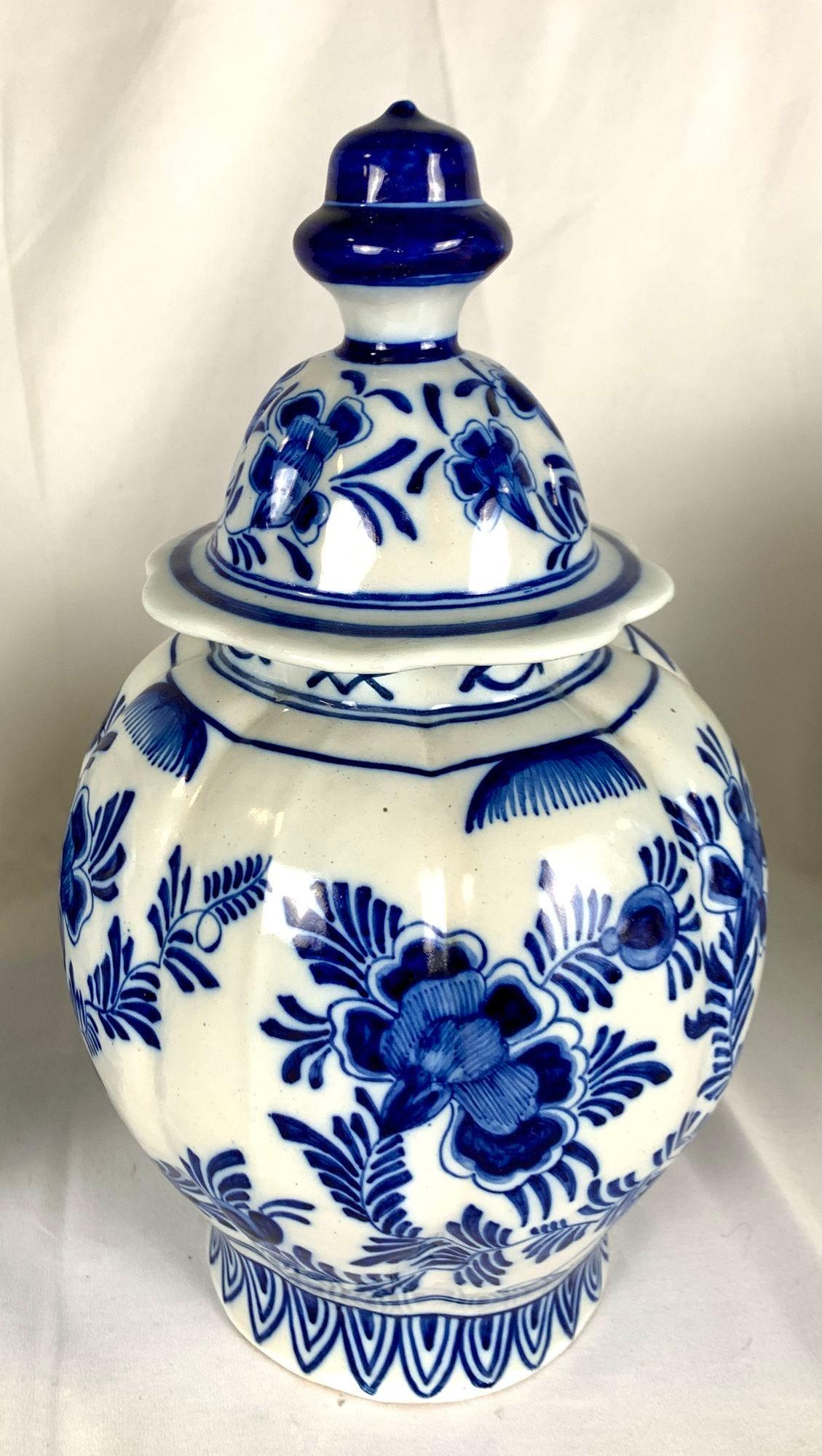 A pair of blue and white Dutch Delft jars hand painted in the Netherlands, in the late 19th or early 20th Century.
Hand painted all around on a lobed body with a chinoiserie scene of a bird perched on rockwork, a figure of an oriental lady, and
