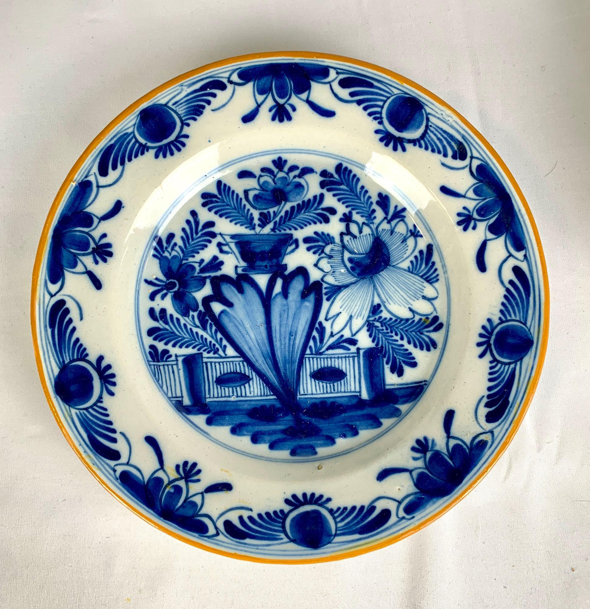 This pair of blue and white Delft plates were hand painted circa 1800 in the Netherlands.
At the center of this lovely pair of dishes is a traditional Dutch Delft view of a garden in full bloom.
We see flowers, ferns, vines, one large peony, a