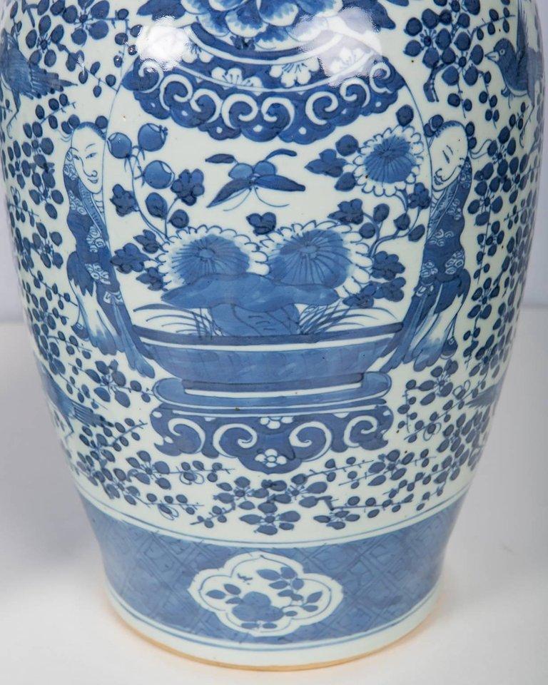 This pair of hand painted blue and white Chinese porcelain jars was made in the late Qing Dynasty circa 1880. 
Each jar is painted in a soft shade of cobalt blue, with a joyful design showing two young boys peeking out from behind a large vase.