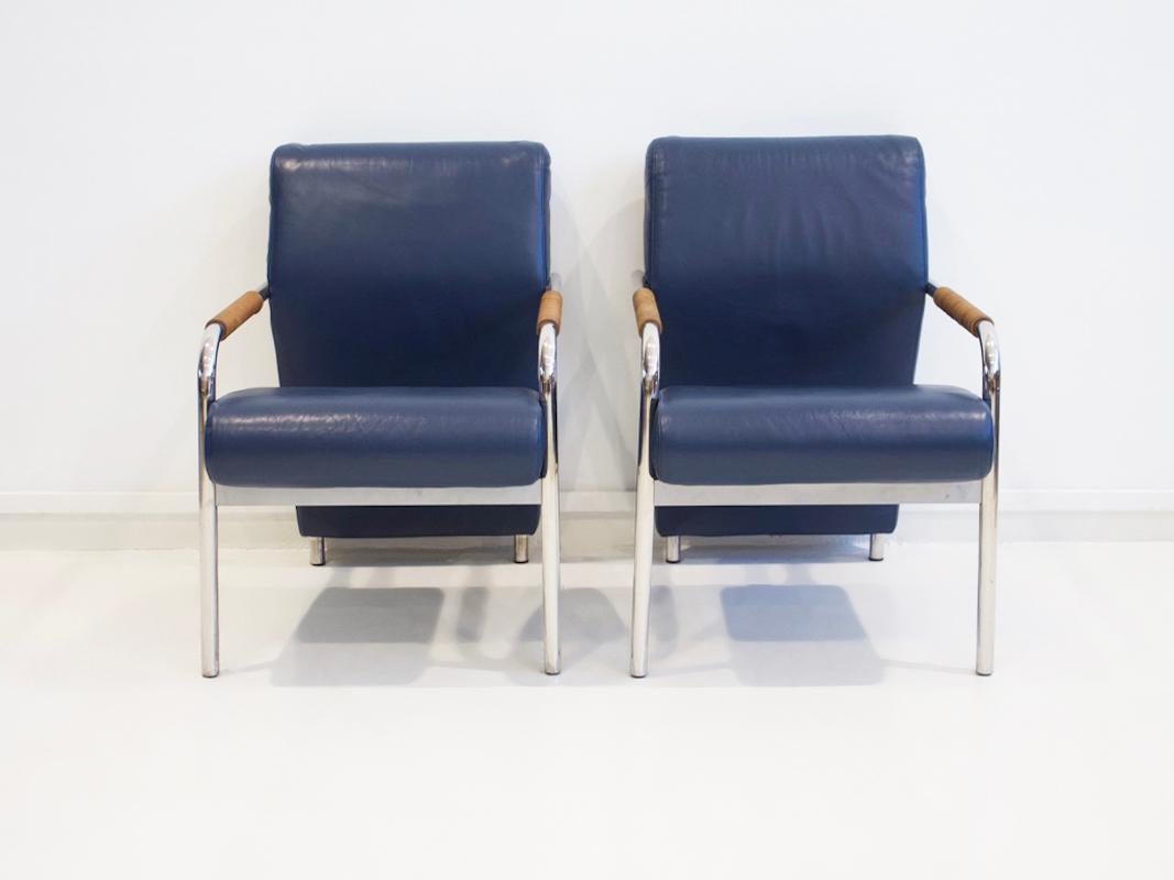 Paire de fauteuils, modèle Niccola, conçus en 1993 par Andrea Branzi pour Zanotta. Construction sur un cadre à quatre pieds en tube d'acier, rembourré et recouvert de cuir bleu foncé, accoudoirs avec galon en cuir marron. Nom du fabricant sous le