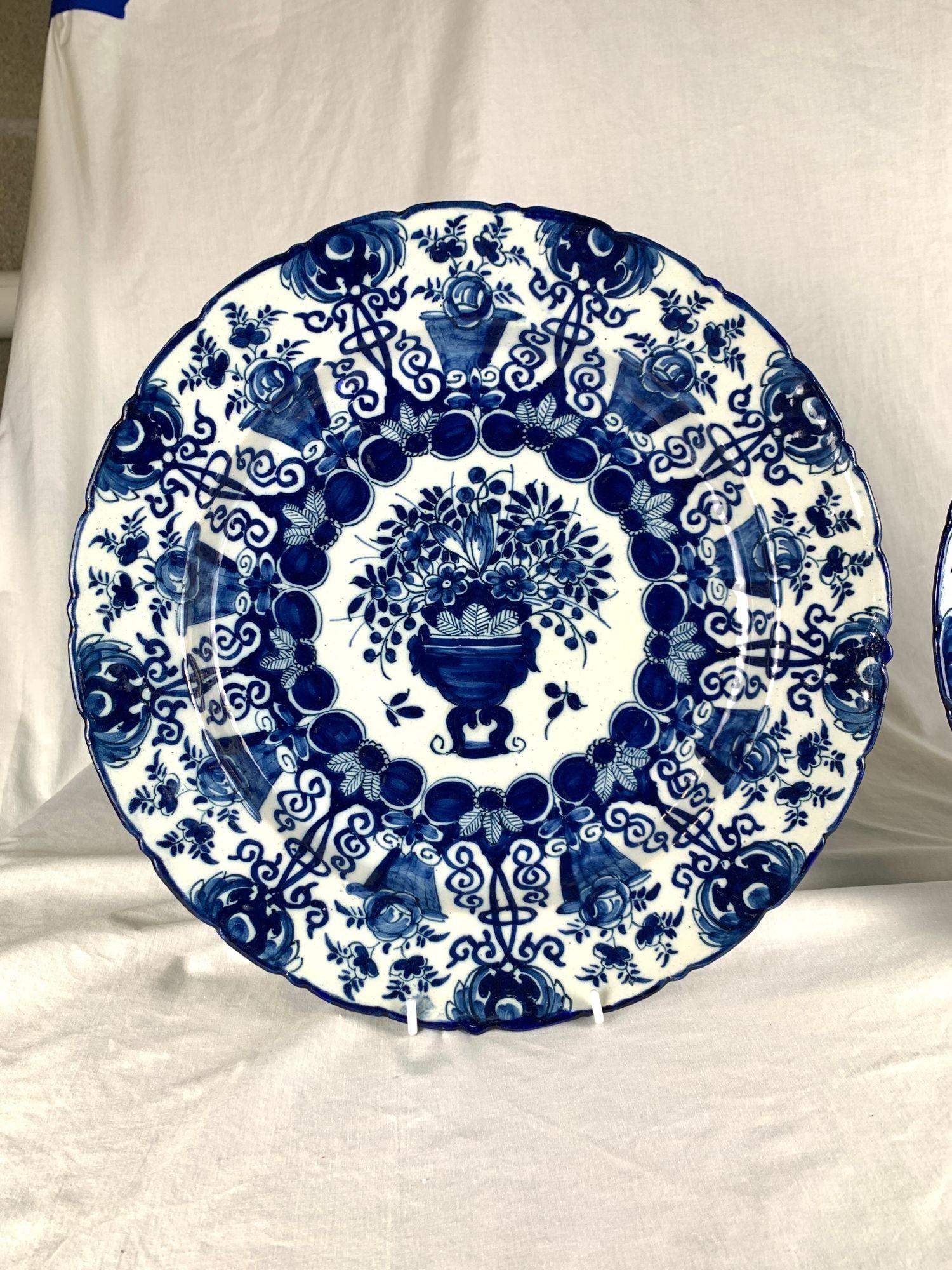 Questa coppia di grandi caricatori olandesi Delft bianchi e blu, dipinti a mano e contrassegnati da De Porceleyne Claeuw (The Claw), è stata realizzata nei Paesi Bassi intorno al 1760.
Ogni caricatore misura 14 pollici di diametro e presenta un'urna