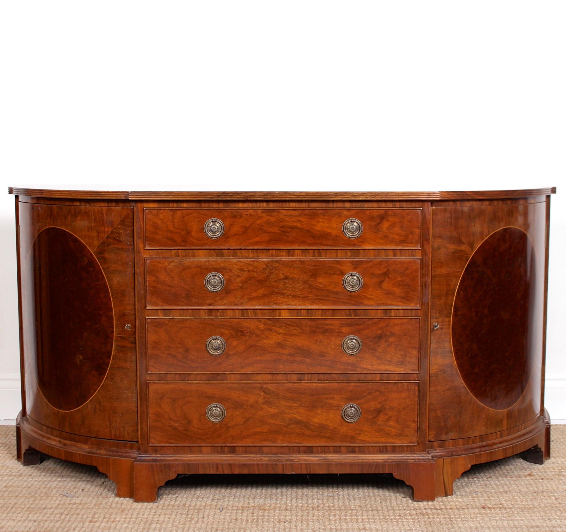 A pair of fine quality bowfront side cabinets.

Constructed from mahogany with magnificent Cuban mahogany and burl walnut marquetry veneers.

A central column of four graduated cock-beaded drawers mounted with good handles, clean oak-lined