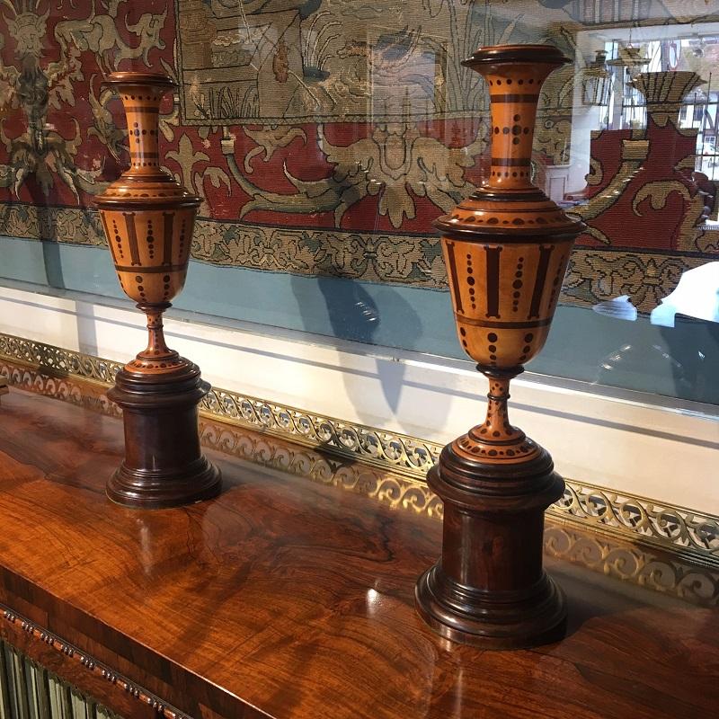 An elegant pair of boxwood chimney ornaments in the neoclassical design. Each is inlaid with purpleheart and raised on a circular turned plinth base which is possibly Lignum Vitae. This extremely hard wood is indigenous to the Caribbean and the