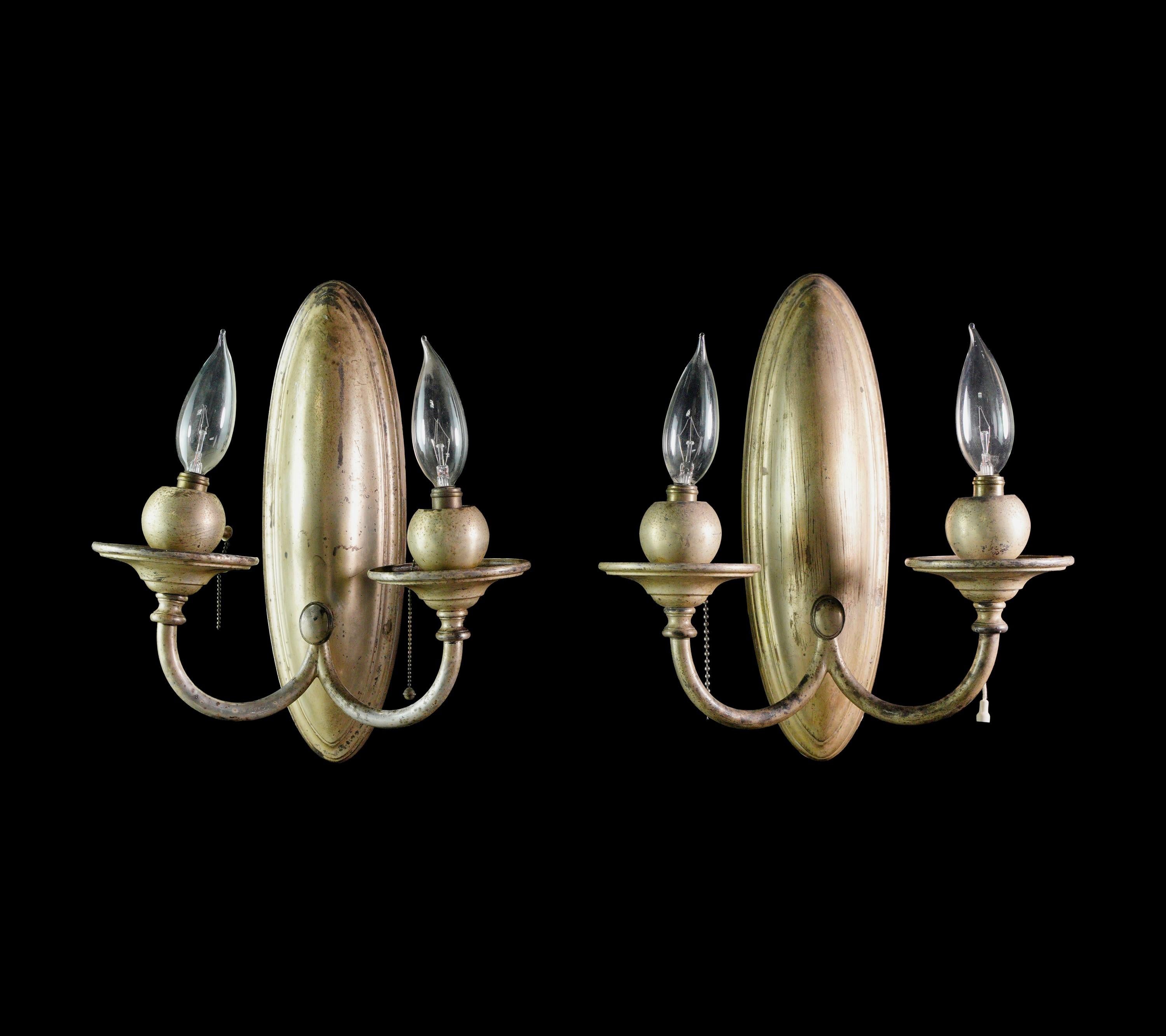 Illuminate your walls with the charm of our pair of antique Traditional Bradley & Hubbard silvered brass wall sconces. With two arms and exquisite silvered brass details, these sconces bring timeless elegance to your space. Cleaned and restored. 