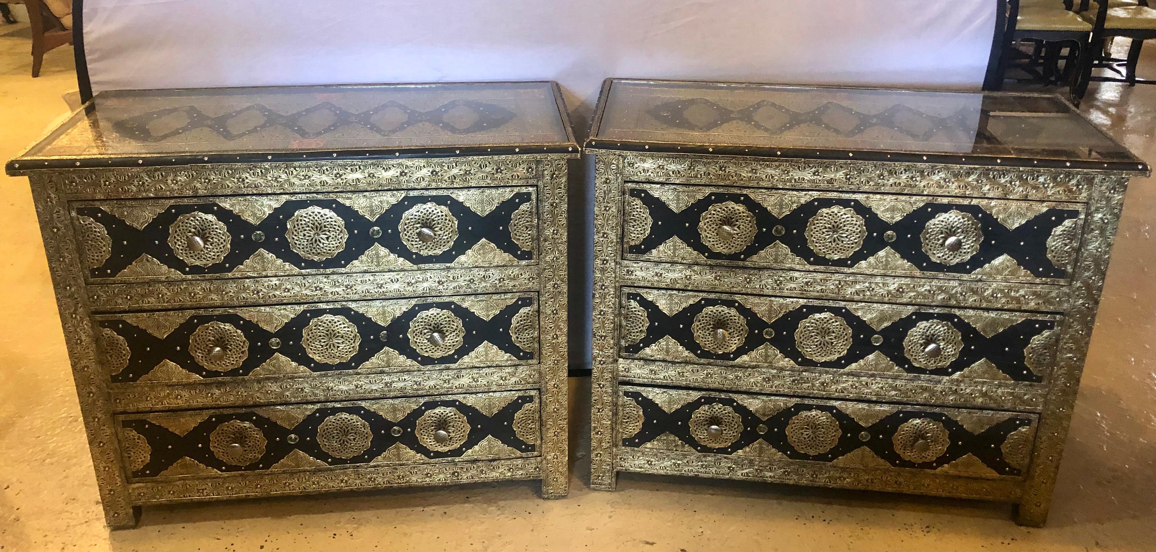 Brass and ebony natural stones and leather inlaid handmade Moroccan commodes.

Pair of brass and ebony natural stone and leather inlaid Moroccan commode, chests or nightstands. These exceptional chests depict and compliment the Hollywood Regency