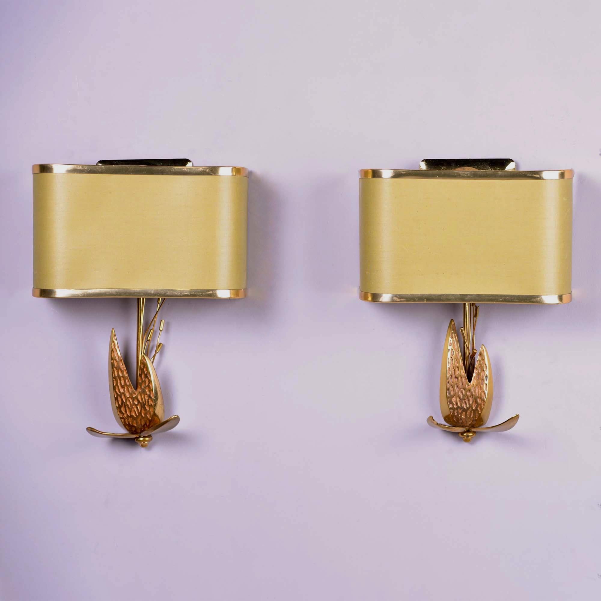 Circa 1970 pair of French wall sconces feature a lotus shaped brass base with original brass trimmed shades. Attributed to Maison Charles. New wiring for US electrical standards. Sold and priced as a pair.