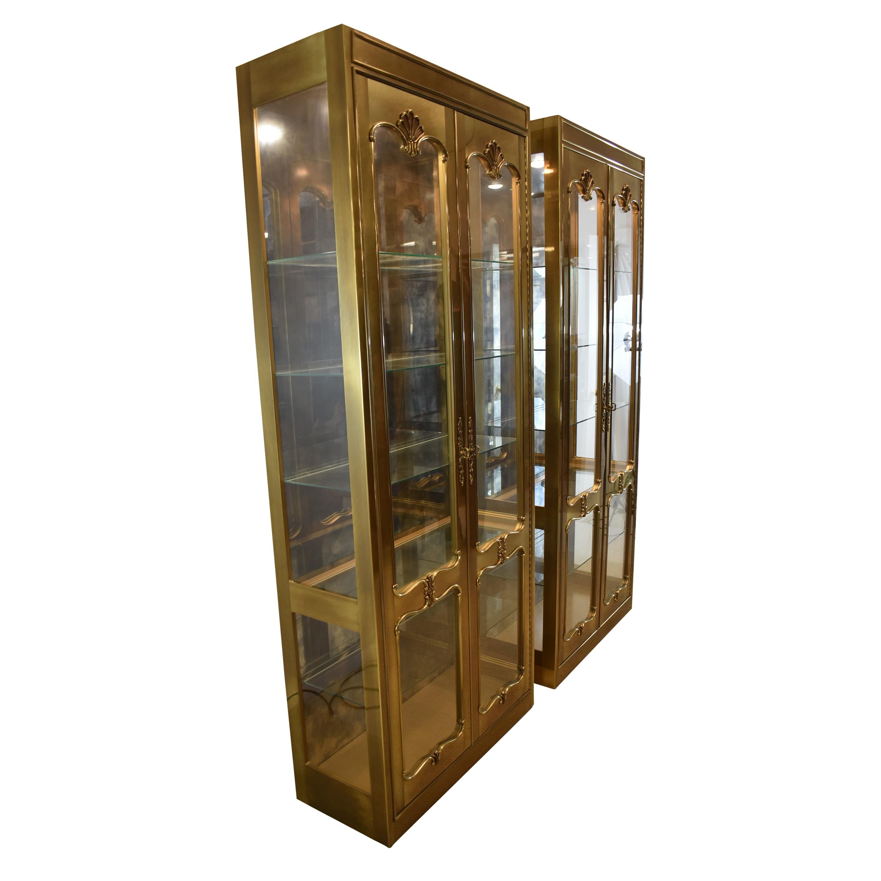 Pair of Mastercraft brass curio cabinets. Double doors open to a lighted interior with adjustable glass shelf.