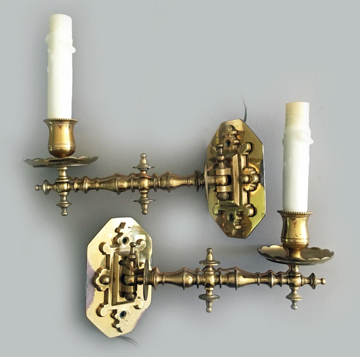 Unusual pair of brass one-light wall sconces in the gothic taste with turnings and decorative finials, scalloped bobeches and wax candle covers.