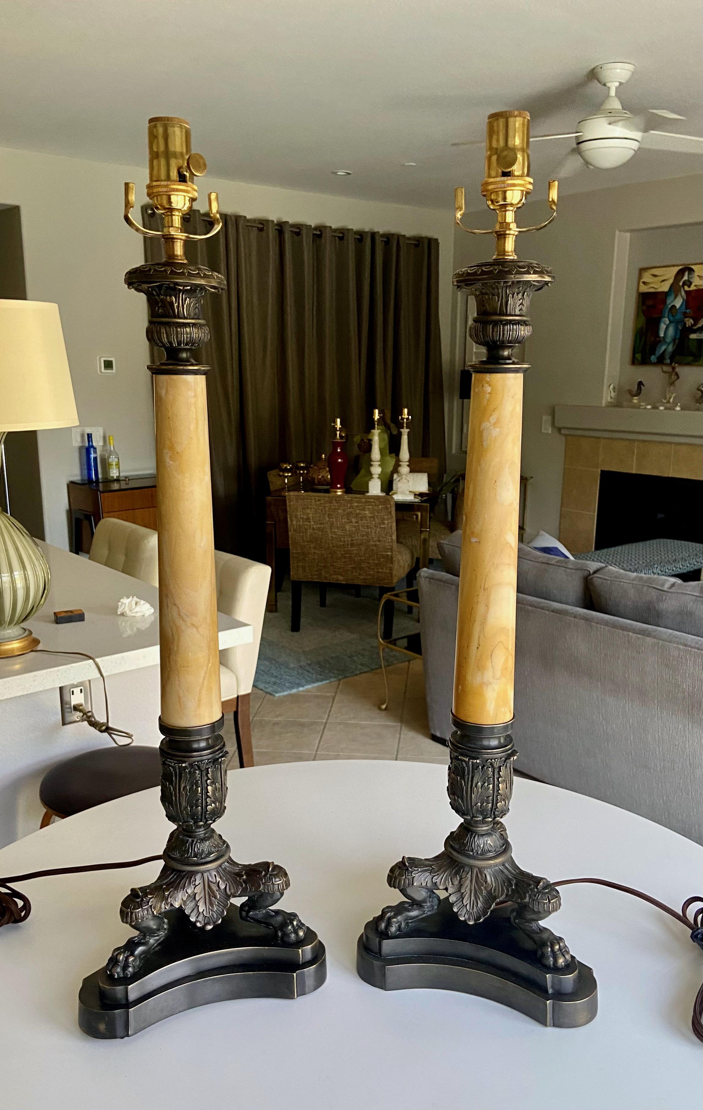 Zwei große Bronzetischlampen im französischen Empire-Stil mit Alabastersäulen auf Löwentatzenfüßen. Die Farbe des Steins ist blass bernsteinfarben mit vielen Farbvariationen und Äderungen. Die Bronze ist fachmännisch gegossen und mit feinen Details