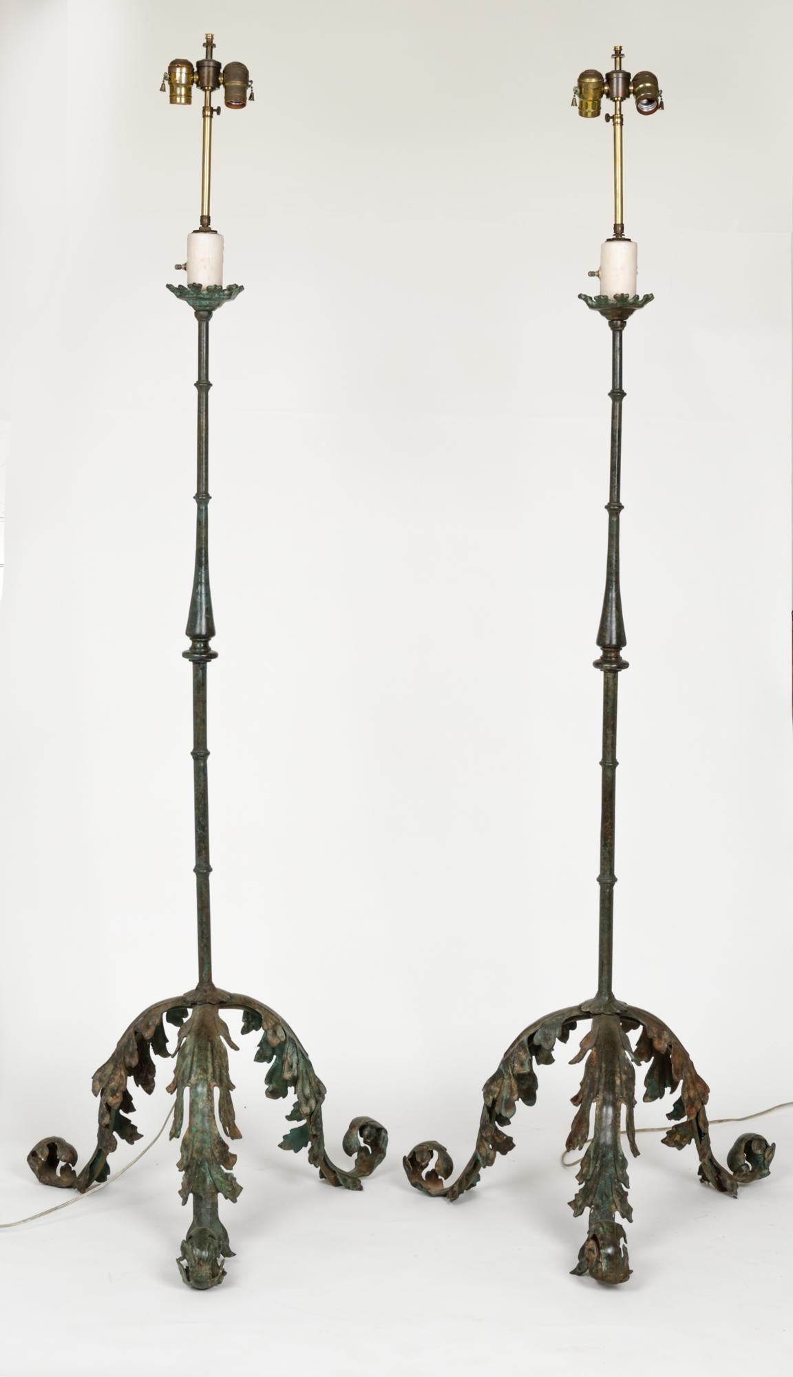 Dramatic pair of floor lamps. Base support is tripod acanthus leaf motif in heavy cast bronze. Contrasted to the simple, elegant posts also in bronze. Beautifully verdigris finish. Shades not included.