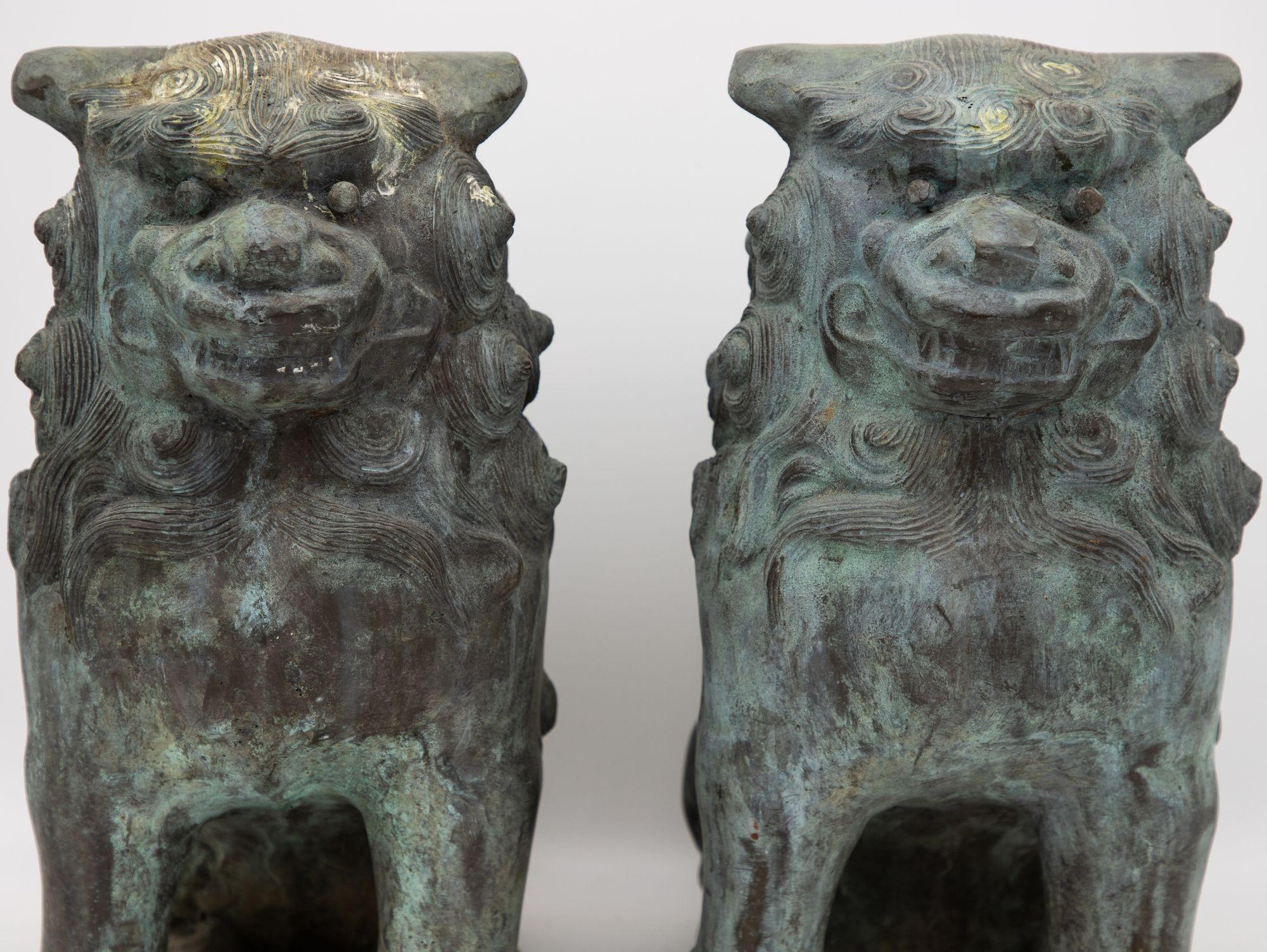 A captivating duo of bronze Foo Dogs, dating back to the early 20th century, exudes timeless charm. These exquisite guardians stand as a testament to artistic craftsmanship, with intricate detailing that brings the creatures to life. The elegant