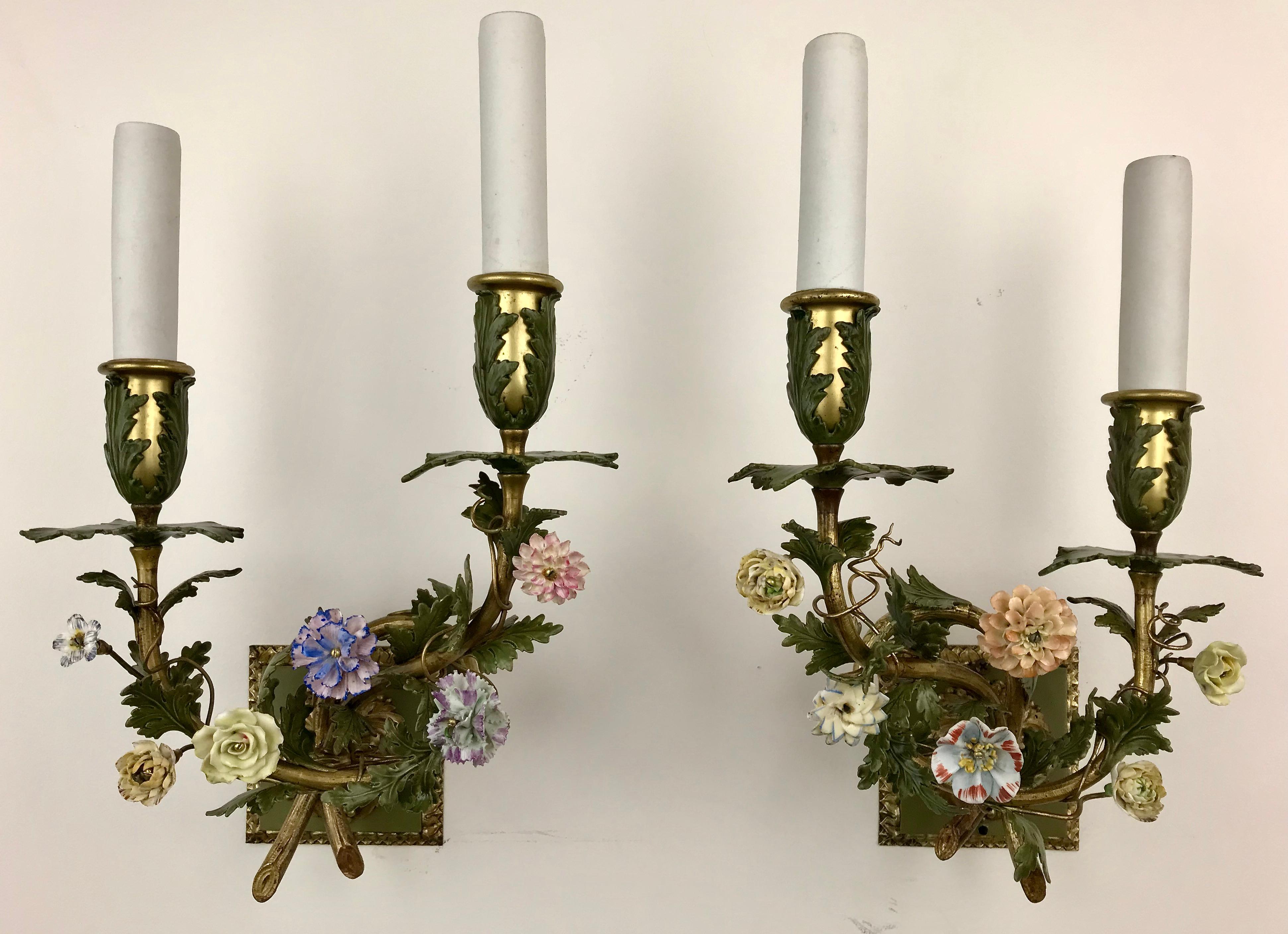 This exquisite pair of two light sconces are by the renown maker Edward F. Caldwell. They feature naturalistic branches with polychrome leaves, and hand painted porcelain flowers.