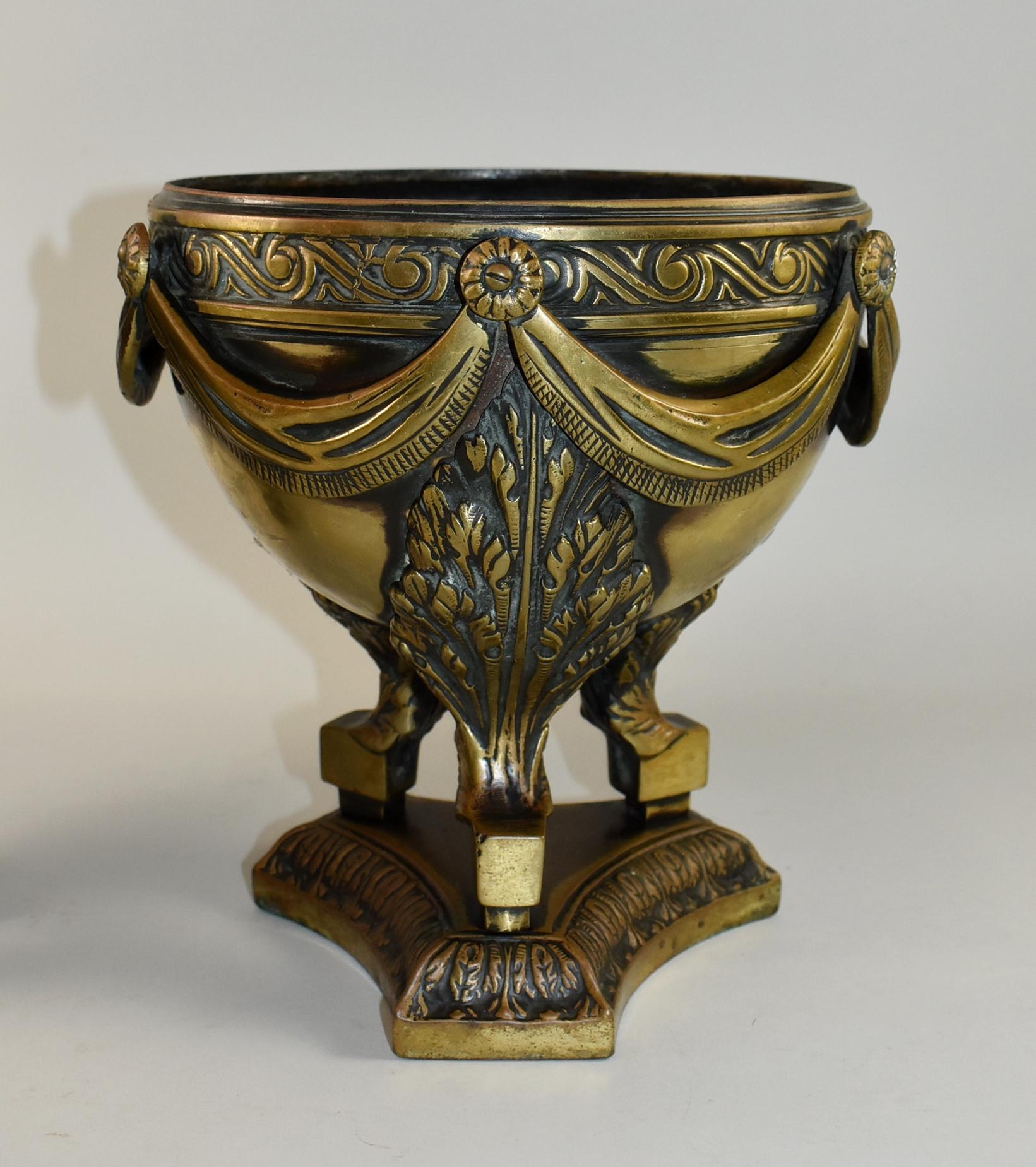Coppia di urne o fioriere in bronzo pesante, circa inizio XX secolo. Sono splendidamente dettagliati con festoni e rosette che circondano il bordo, piume su ognuna delle tre gambe del treppiede e foglie intorno alla base della piattaforma. 15,5