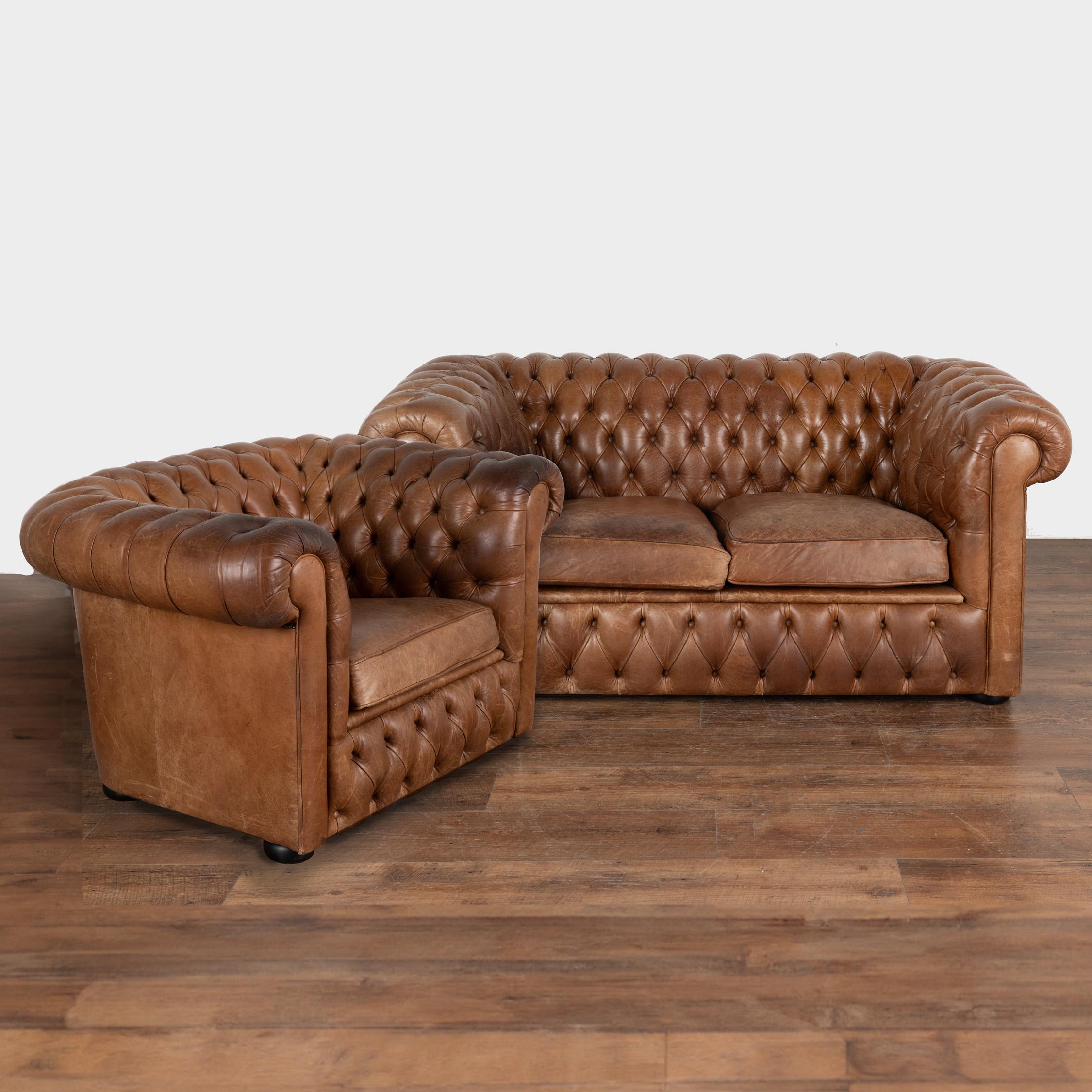 Loaded with character, this two seat sofa and club chair packs a vintage punch with the classic lines and tufted back of a classic Chesterfield sofa with self covered buttons and heavy rolled arms.
The vintage brown leather shows typical age related