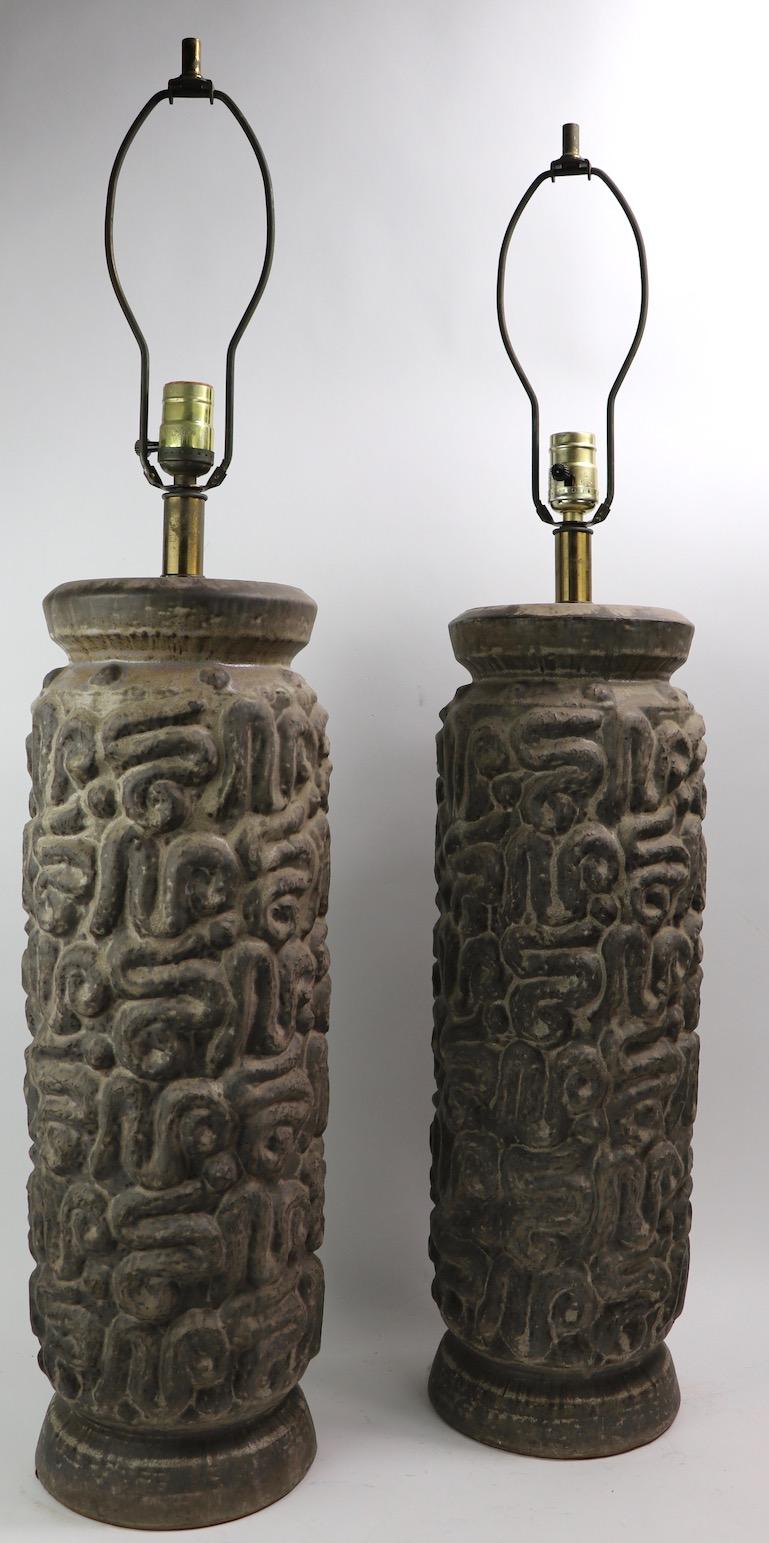 Wonderful pair of Brutalist ceramic table lamps with raised relief surface and earth tone finish. Very stylish and chic, great original and working condition, clean ready to use. Height to top of ceramic body 22 inches x Total H 36 inches. Shade not