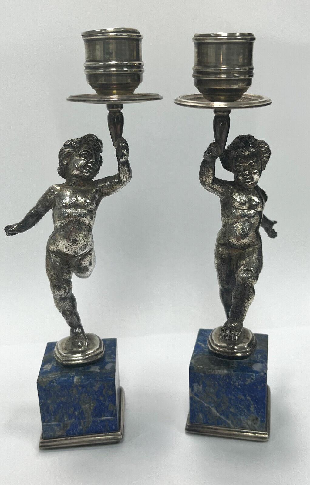 Pair Buccellati Italian sterling silver and Lapis Lazuli veneered candlesticks, circa 1950. Figural cherubs to the stem holding up the bobeches in a dancing manner. Venered Lapis Lazuli panels to the bases. Buccellati Italian sterling silver marks