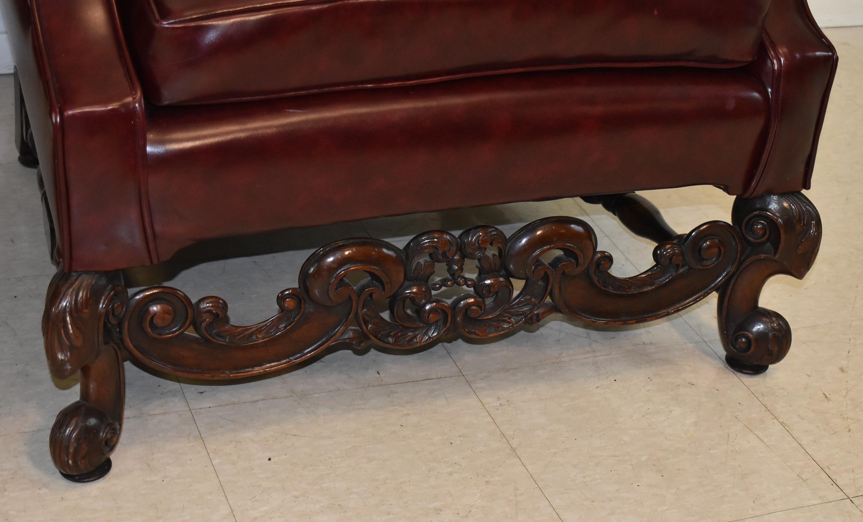 Pair of burgundy wing back club chairs with heavily carved walnut frame. Circa 1920's. Very solid, dark burgundy, great condition. Chairs are 42