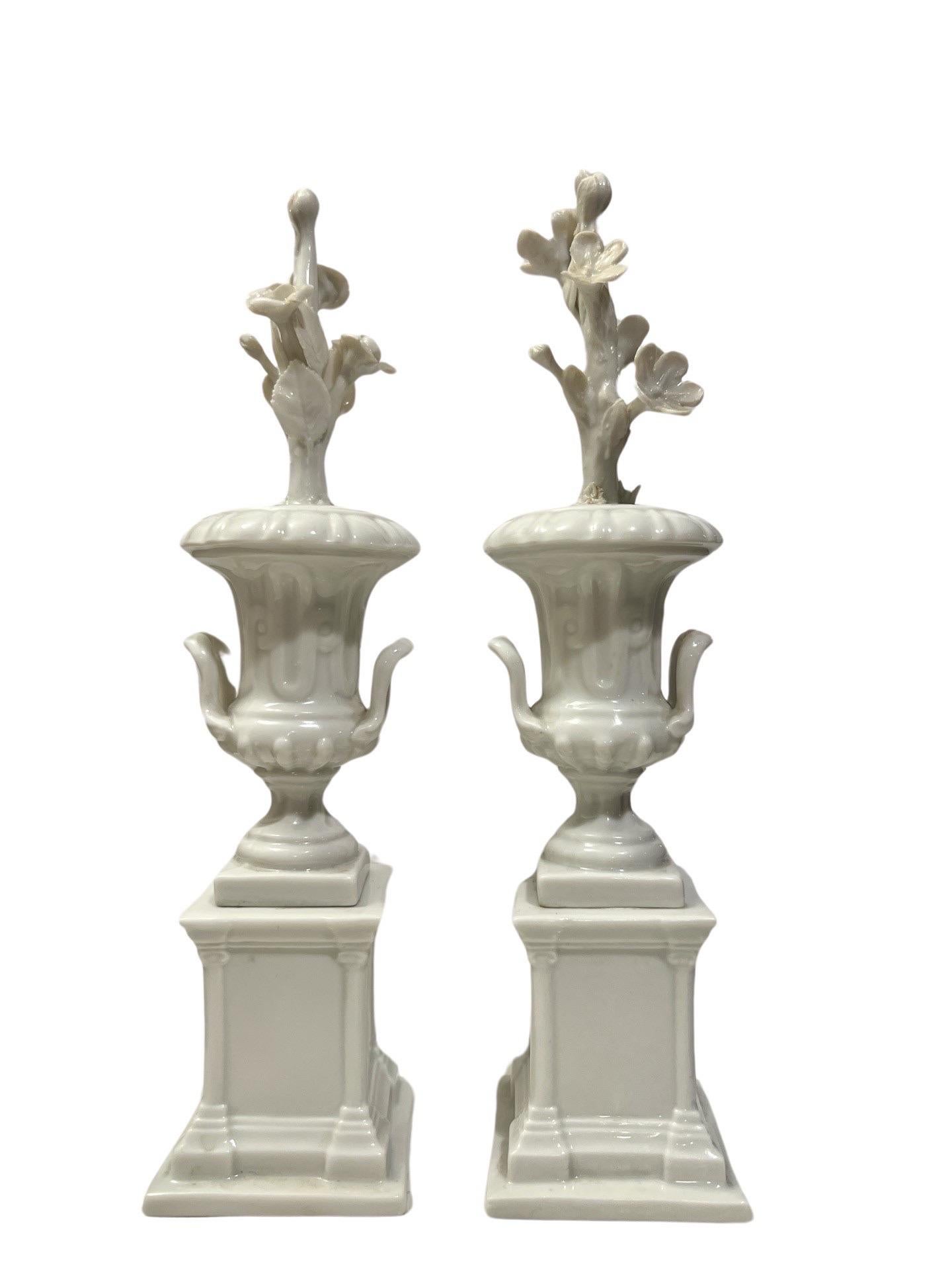 Italian, 20th century. 

A pair of petite blanc de chine porcelain urns with floral stem motif extending from each. Marked to underside with the Capodimonte blue mark.