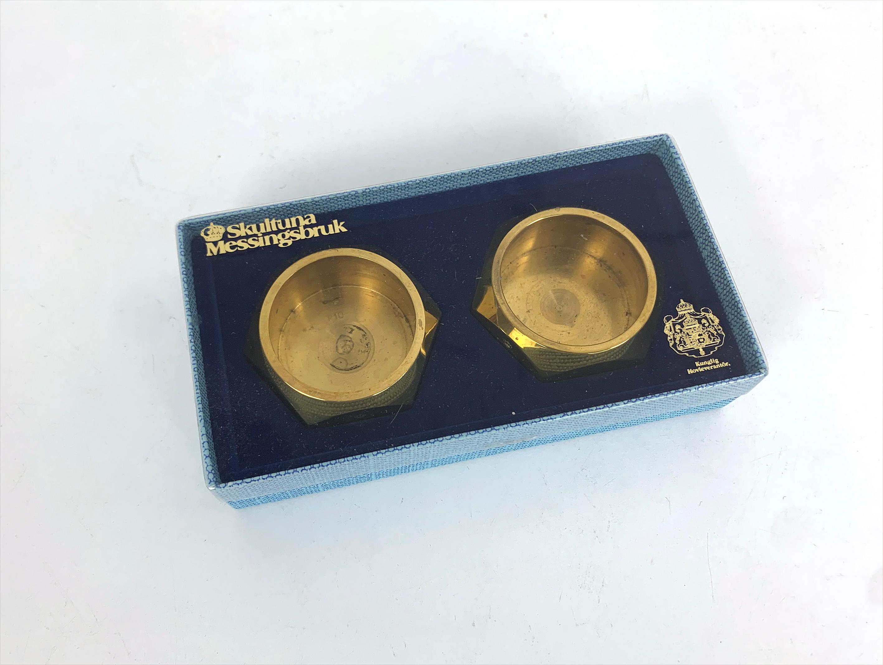 Ein Satz von 2 sechseckigen Kerzenhaltern Modell N°10 für Teelichter, in ihrer Originalverpackung. Hergestellt aus massivem Messing.  

Der Entwurf wird Pierre Forssell zugeschrieben und in Schweden von Skultuna hergestellt. Das Unternehmen wurde