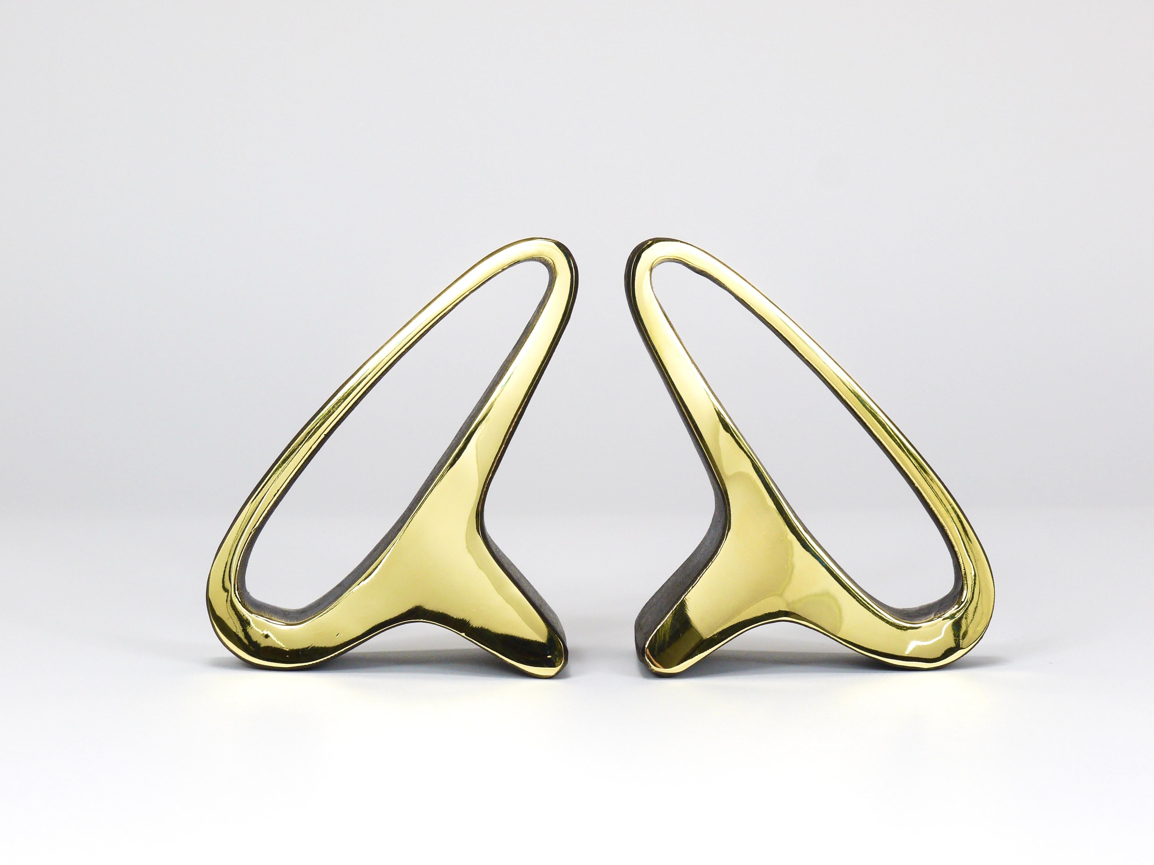 A pair of minimalist sculptural bookends in an organic form, lovingly referred to by Auböck as “earlobes.” Model number 3848. Handcrafted from solid brass with a patinated and polished finish, each piece reflects the traditional craftsmanship.