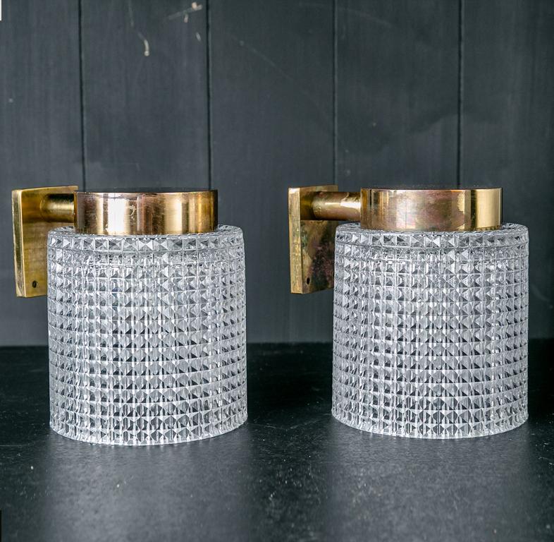 This pair of Orrefors sconces is of heavy glass and aged brass. The glass is a full cylinder. They are of Classic, timeless midcentury style.