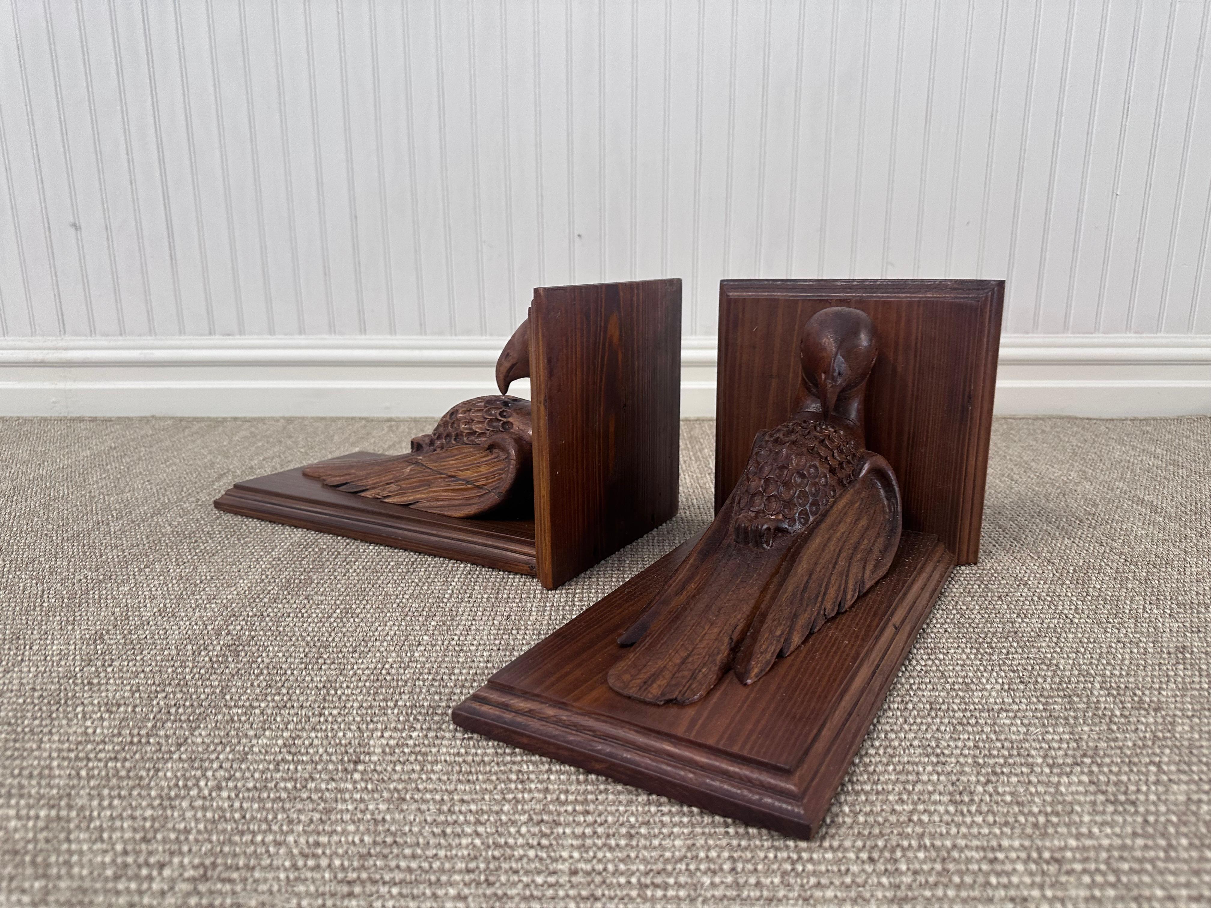 This image features a pair of carved wooden bookends designed in the shape of parrots or pigeons. Each bookend showcases a birdin a resting pose with its wings folded and head slightly bowed, facing inward toward the books or wall they would