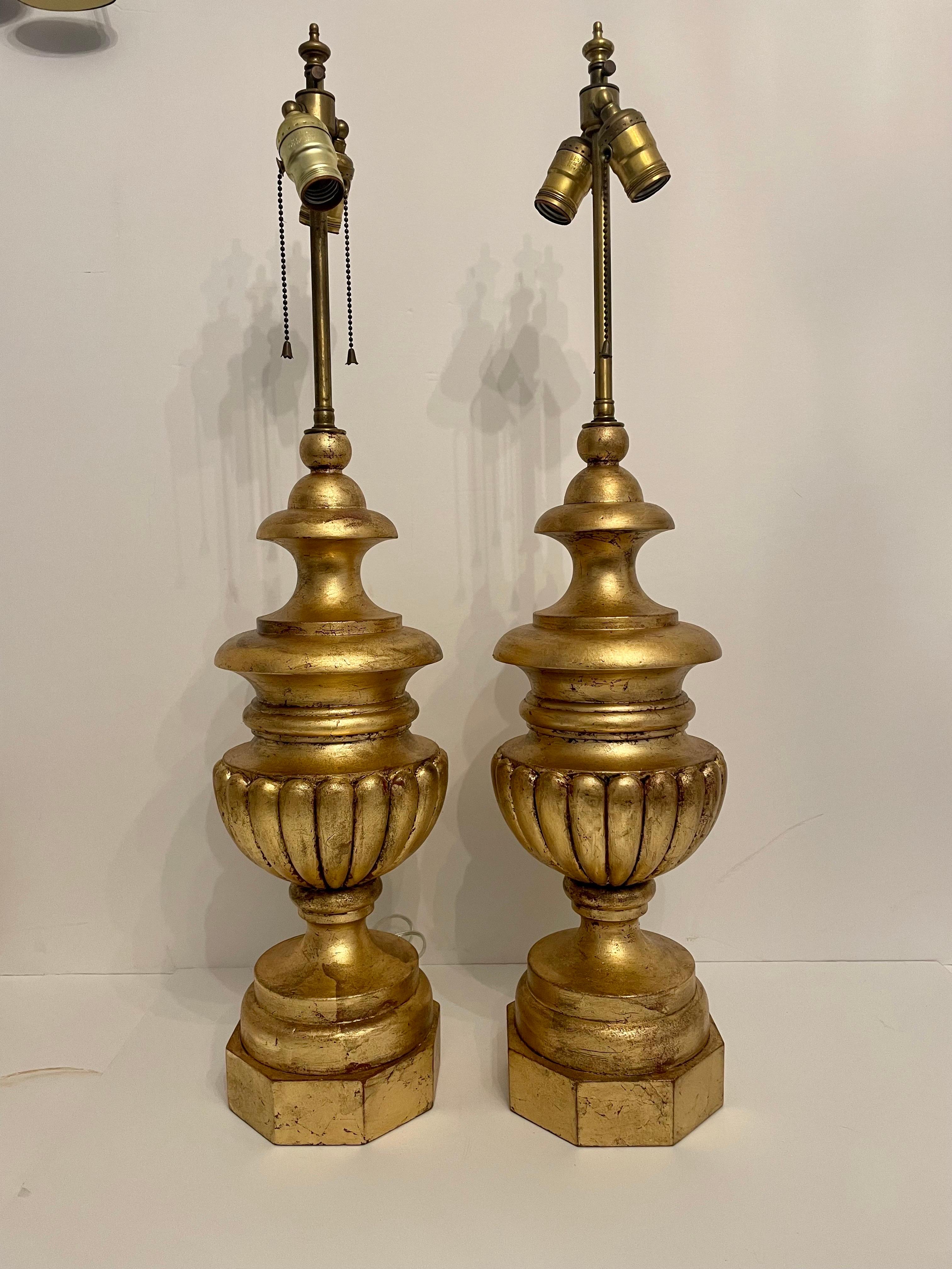Pair of Hollywood Regency style carved gilt table lamps, circa 1950-1960s. Please note of wear consistent with age including some wear to finish due to use. Shades not included. The lamps measure 31