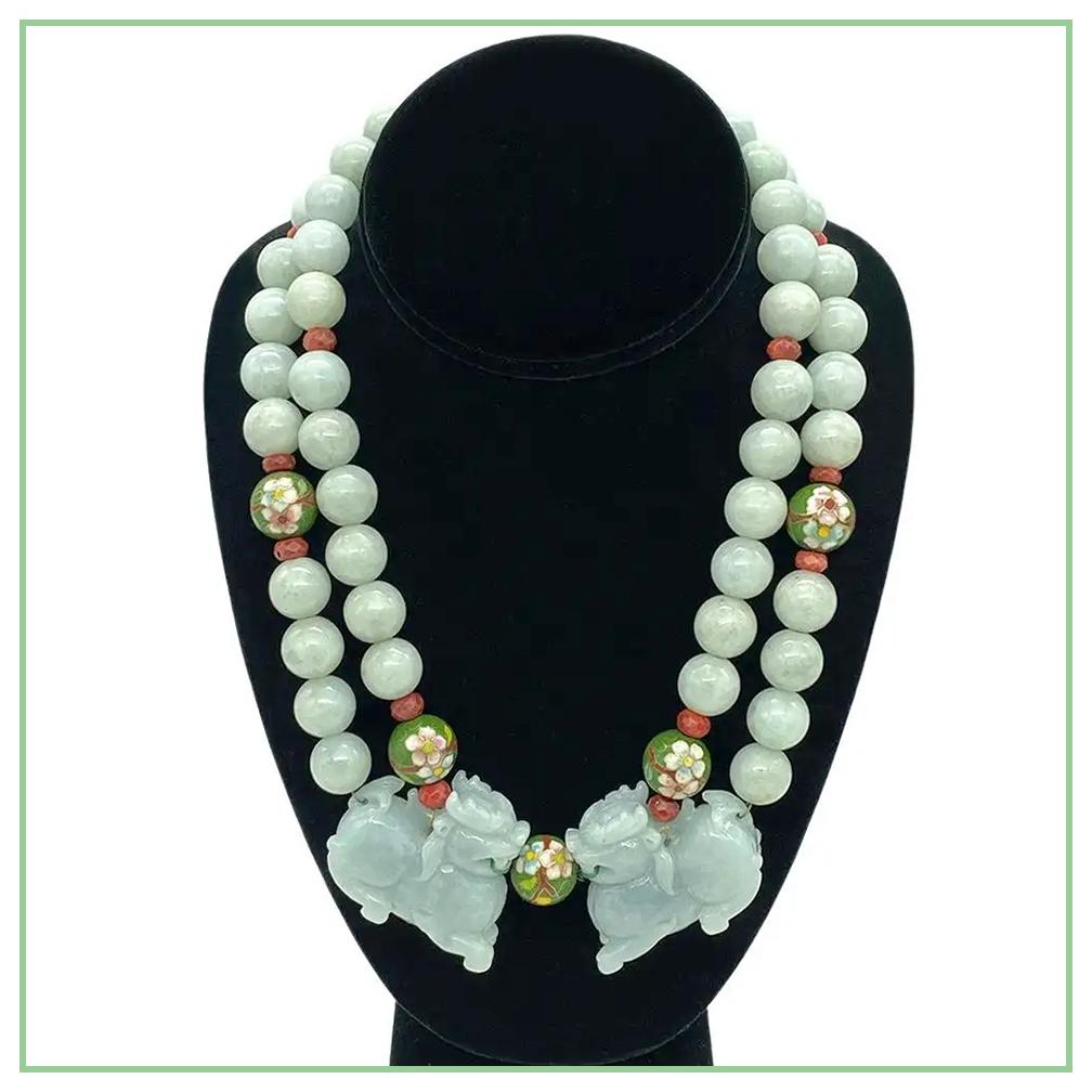 This is a double strand jade necklace with Foo Dog pendant. We created it with 14 mm smooth jade stone beads and decorated it with 15mm vintage cloisonné beads and 8 mm faceted coral rondels. The necklace is connected with a pair of caved lavender
