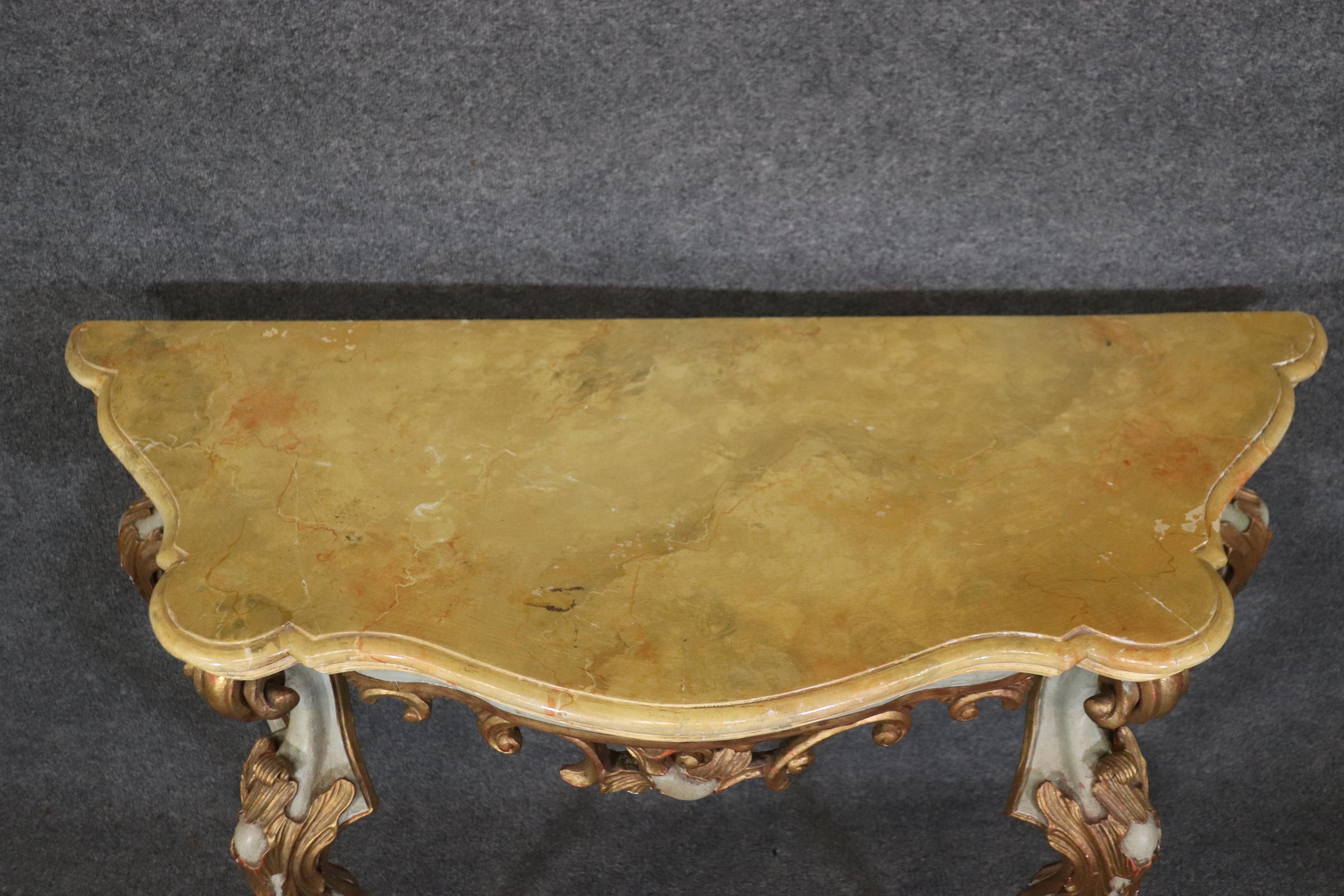 This is a superb pair of paint-decorated Italian-made Rococo console tables. The tables feautures beautifully painted faux marble tops. The tables feature a glorious paint scheme including gilding and various hues of ochres, and pastels. The tables