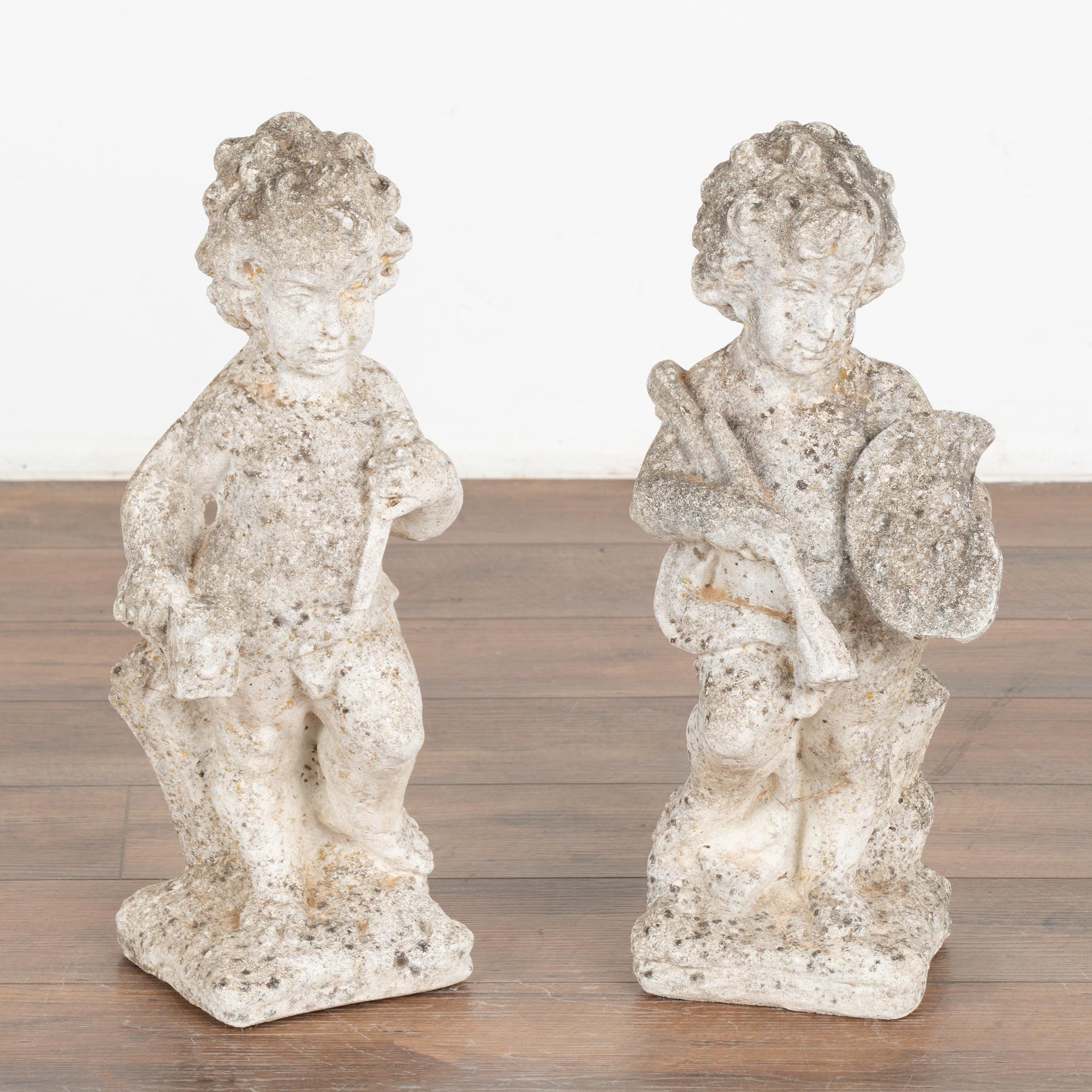 Pair of carved limestone garden sculptures. One putti is holding a mallet and chisel while the other holds a paint brush and artist's pallet. Note the fine details in the carved faces.
The worn patina reflects years of exposure outside in the