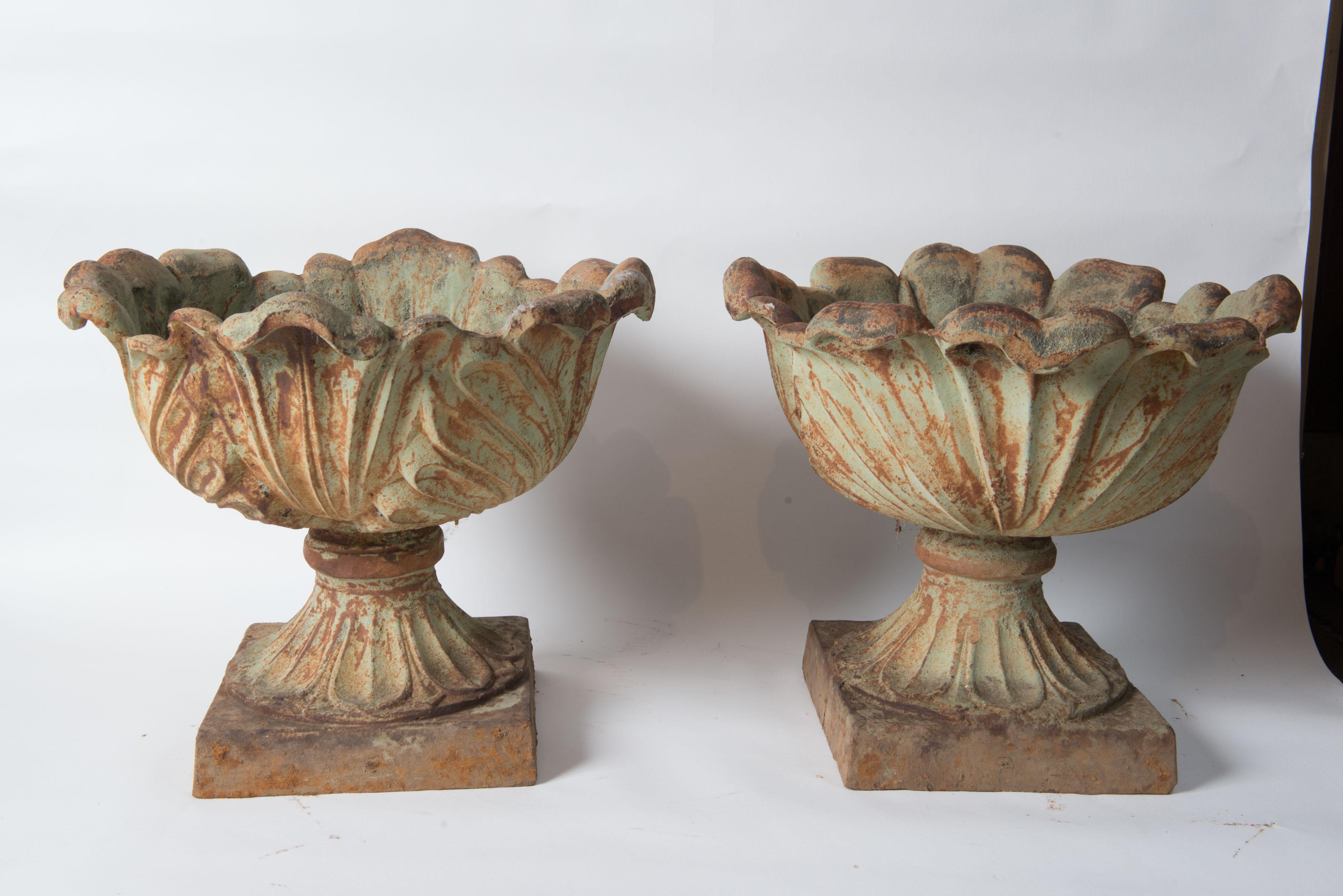 Pair of unusual foliate designed cast iron American urns or planters. A large detailed leaf pattern decorates these urns creating an organic scalloped floral like edge. Small area of base detail is worn on one urn. See photos. 0.5