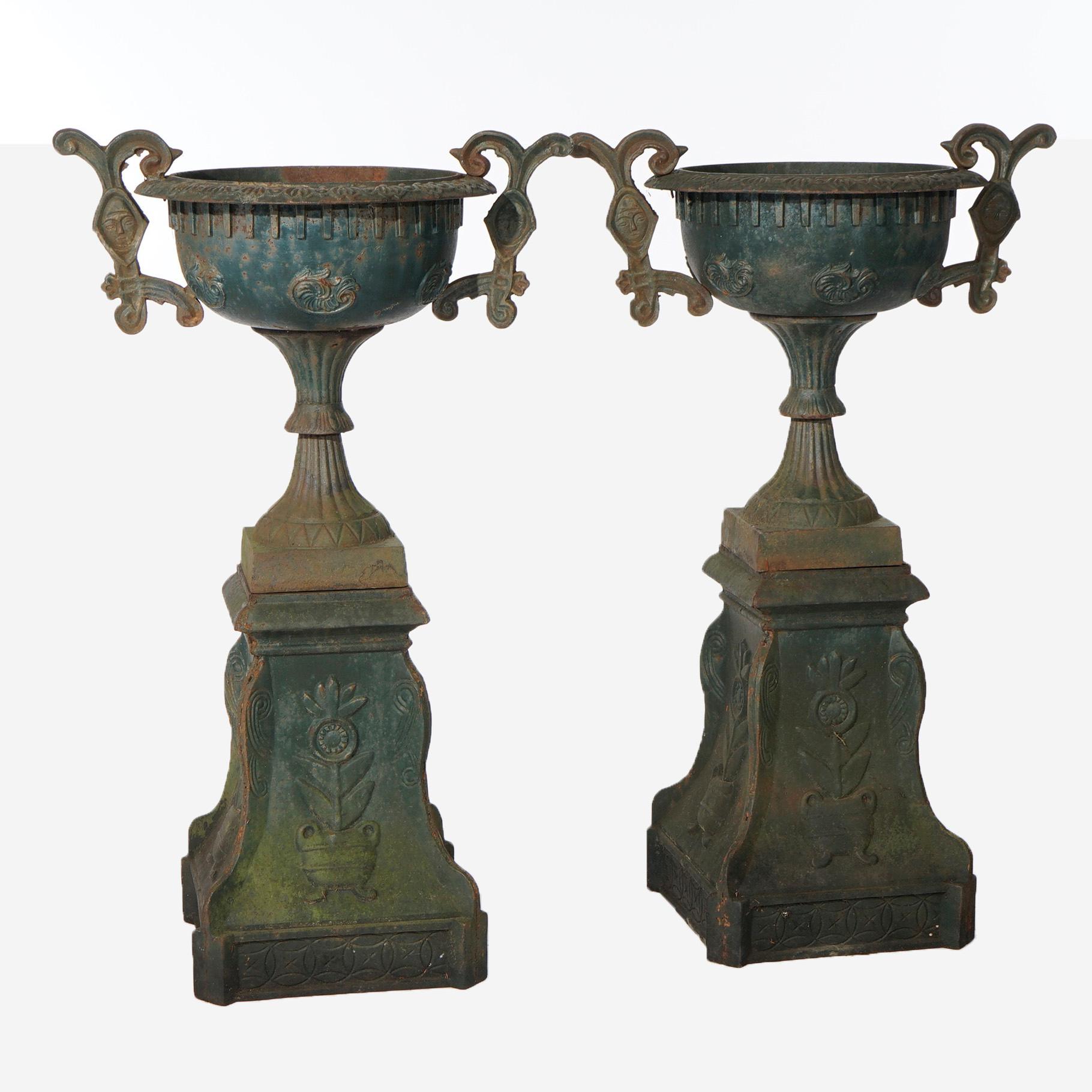 A pair of Grecian cast iron garden urns offer foliate embossed bowls with flanking scroll form handles having central mask, raised on floral embossed plinths, 20th century

Measures- 41.5''H x 24.75''W x 24.5''D

*Ask about DISCOUNTED DELIVERY rates