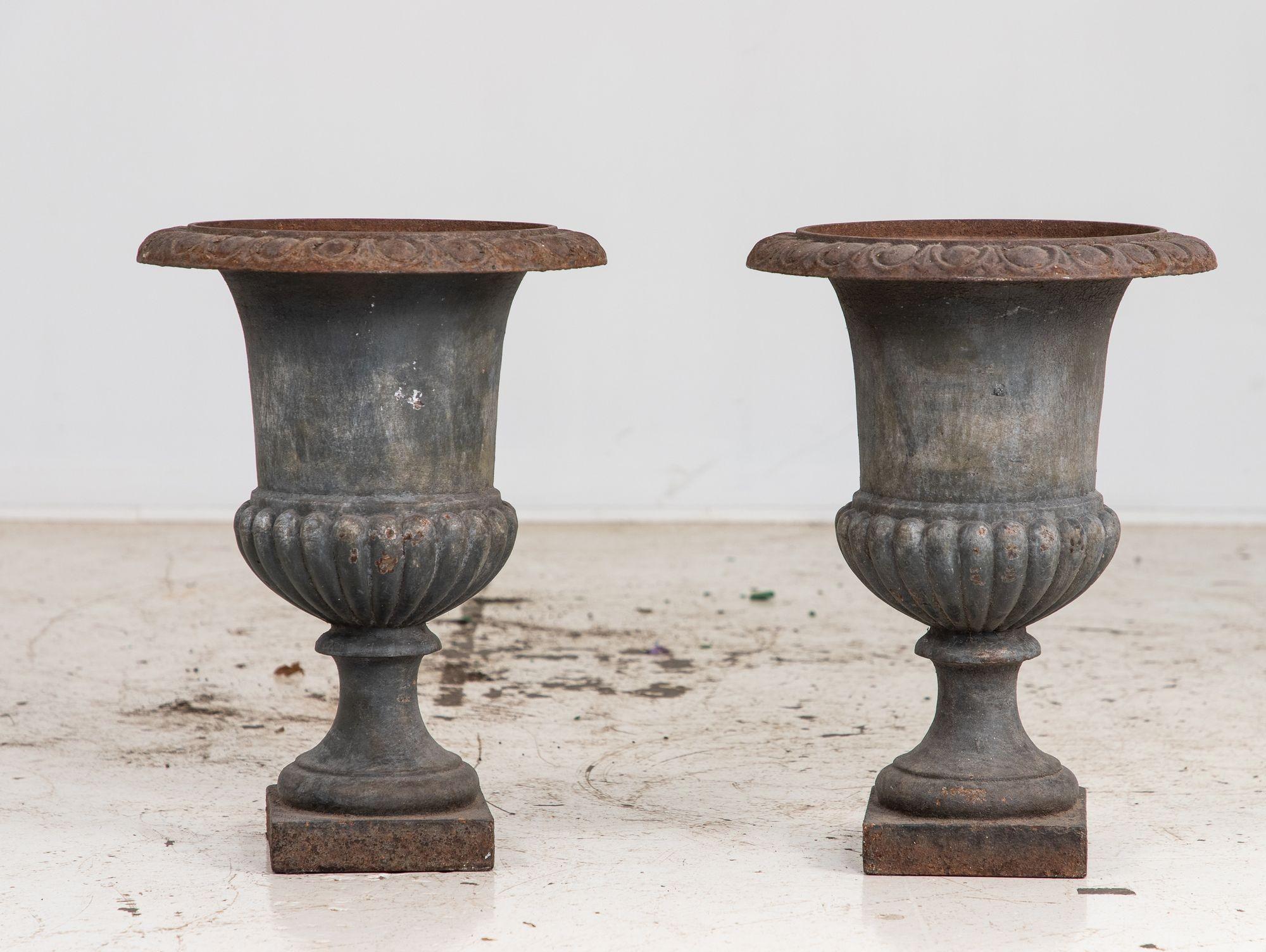 Paire d'urnes en fonte de style néoclassique français, datant du milieu du 20e siècle. Dotées de proportions élégantes et d'un design intemporel, les urnes présentent une finition grise qui renforce leur attrait classique. Ces pièces présentent une